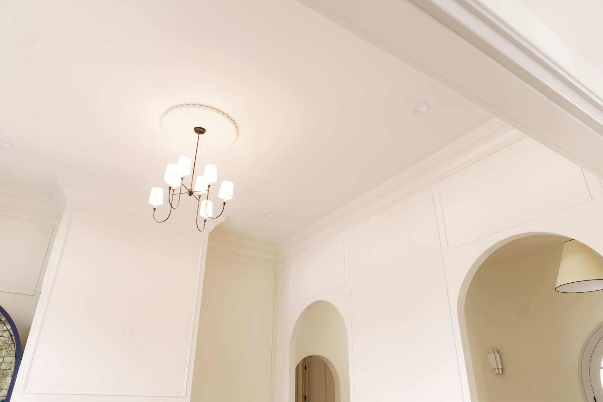 A chandelier is hanging from the ceiling of a white room.