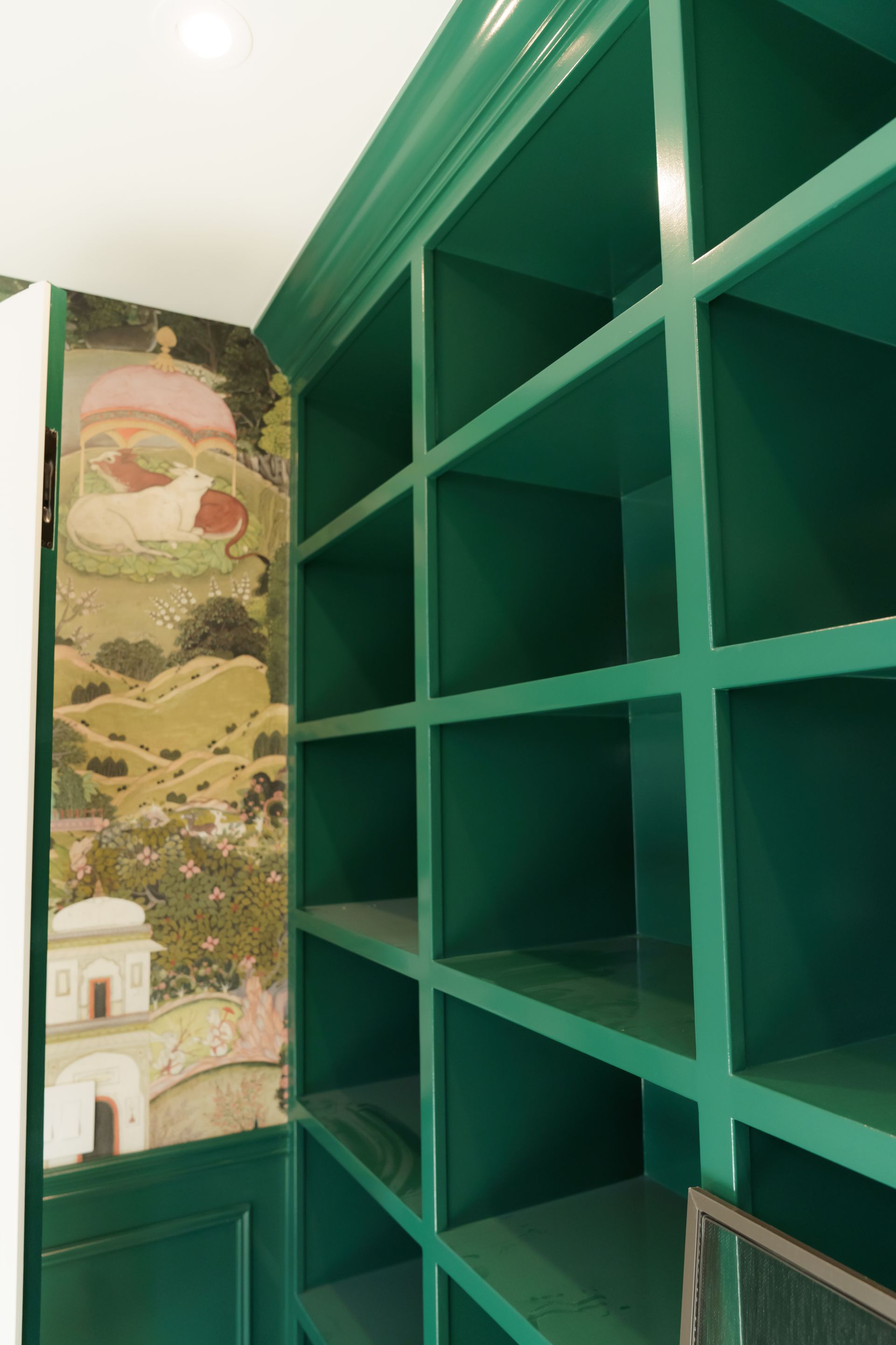 A room with green shelves and a painting on the wall