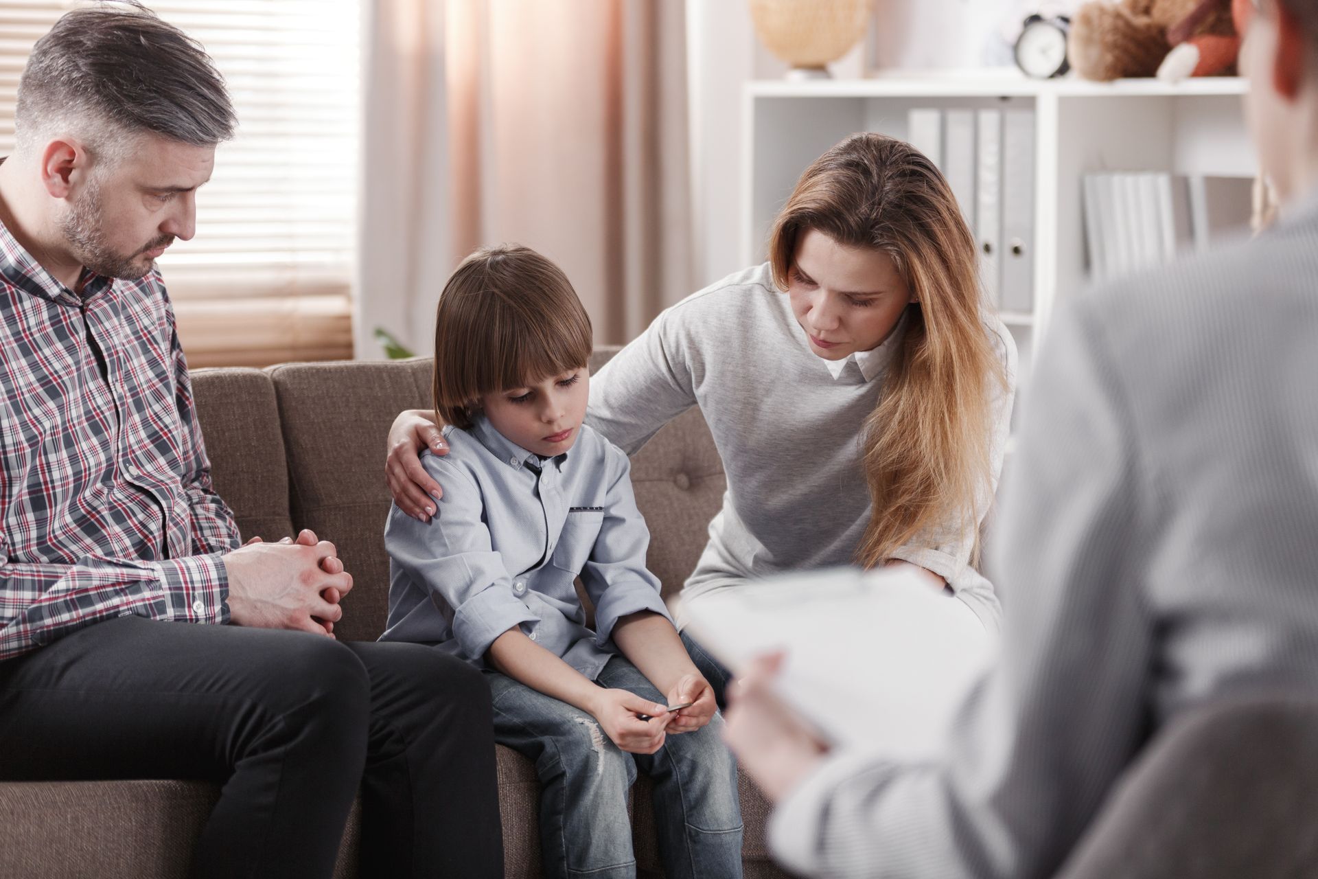A family is sitting on a couch talking to a counselor.