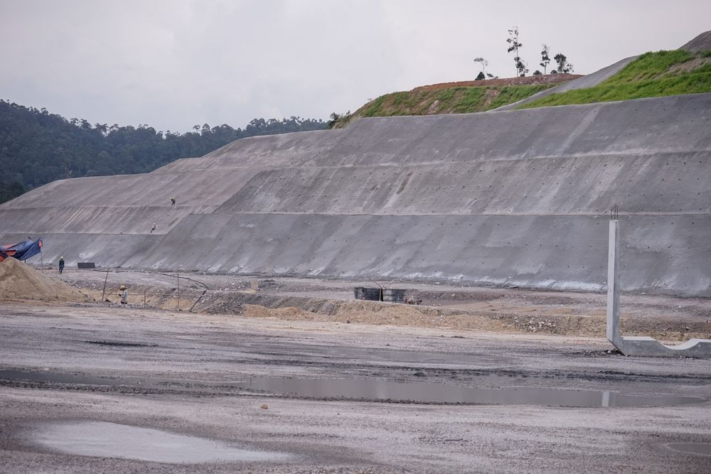 A tiered concrete retaining wall built into a hillside, part of a construction site.