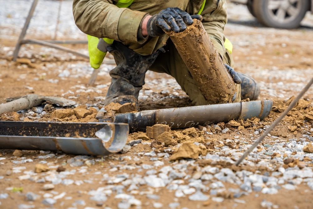 Person examining a soil sample from a drilled core in a construction setting.