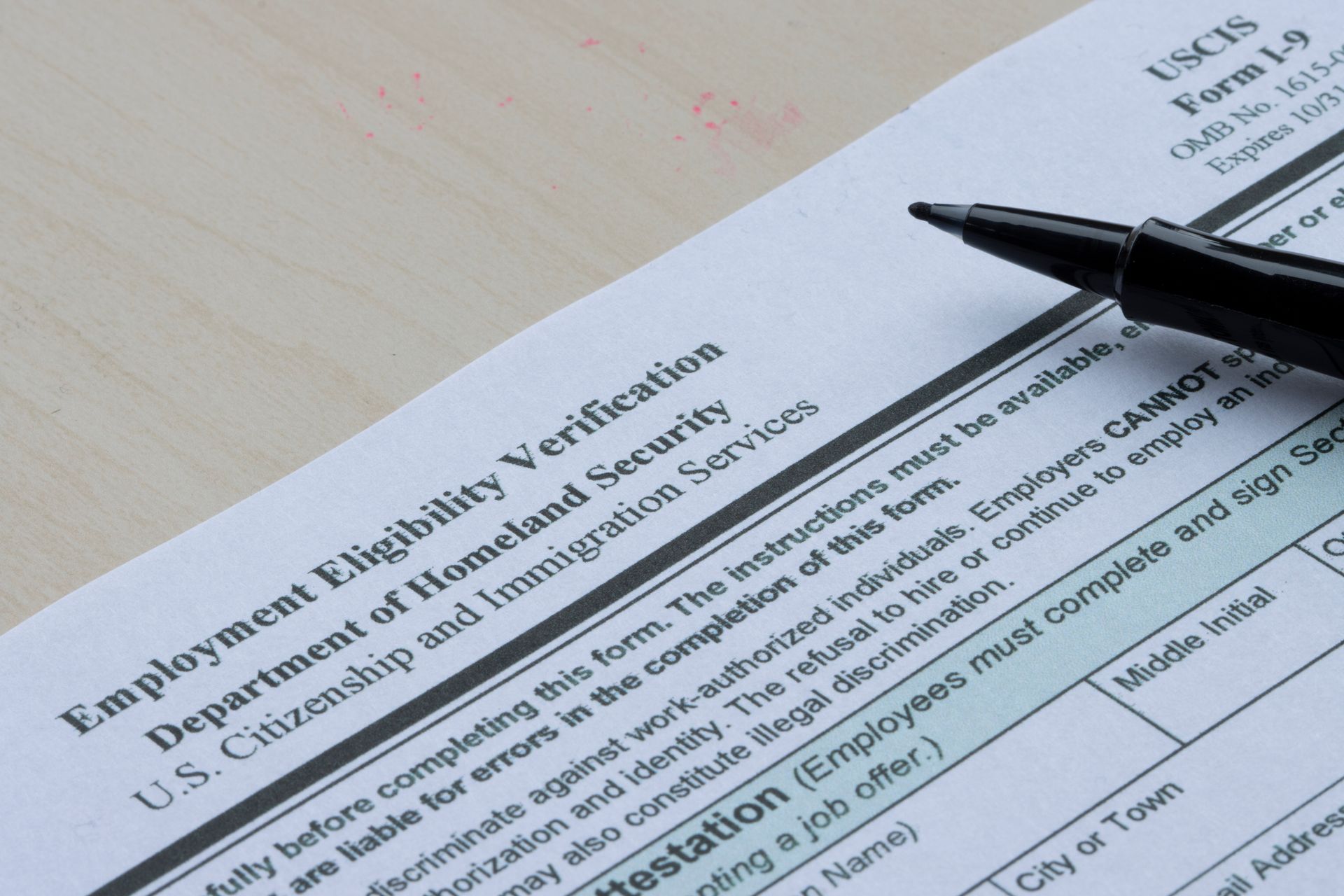 A pen rests on top of a employment eligibility verification form
