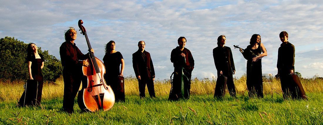 Chamber Philharmonia Cologne standing in a field with instruments.