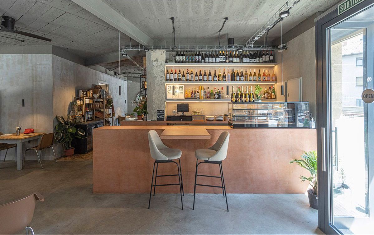 Fotografia Emfasi Estudi Andorra. Un restaurante con mesa y sillas frente a una barra.