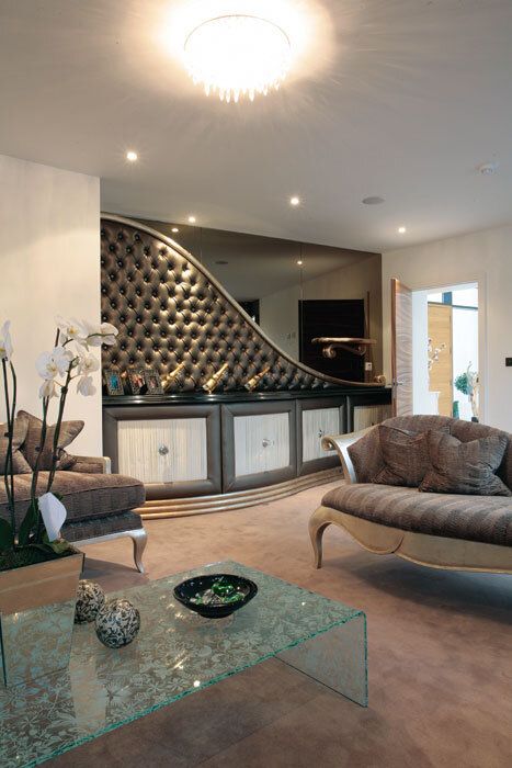 Elegant living room with curved tufted wall, bar, and ornate furniture.
