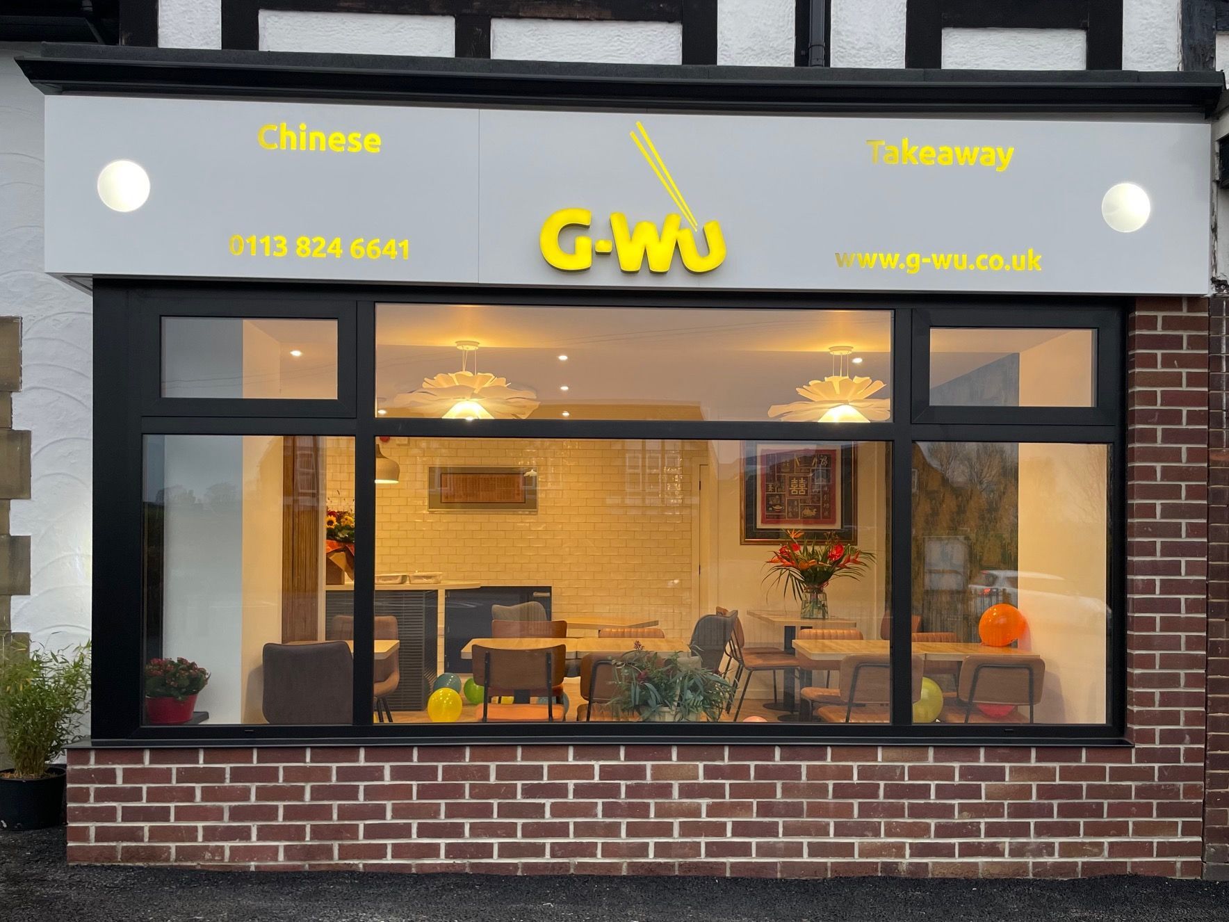 G-Wu Chinese takeaway storefront with illuminated sign and window display.