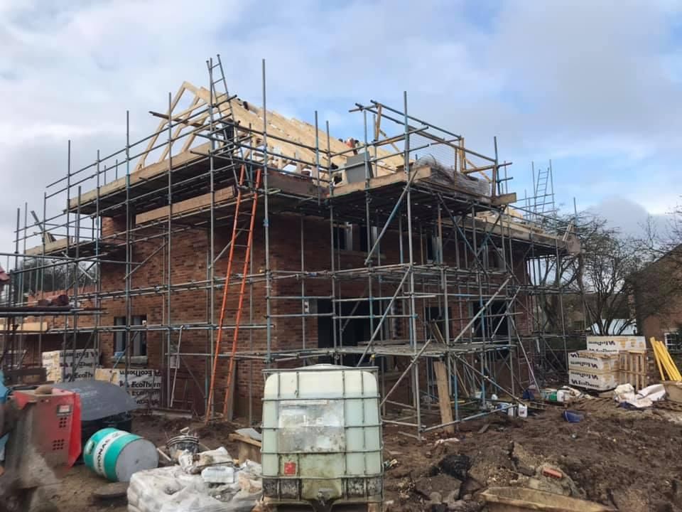 Brick house under construction, scaffolding surrounding the building.