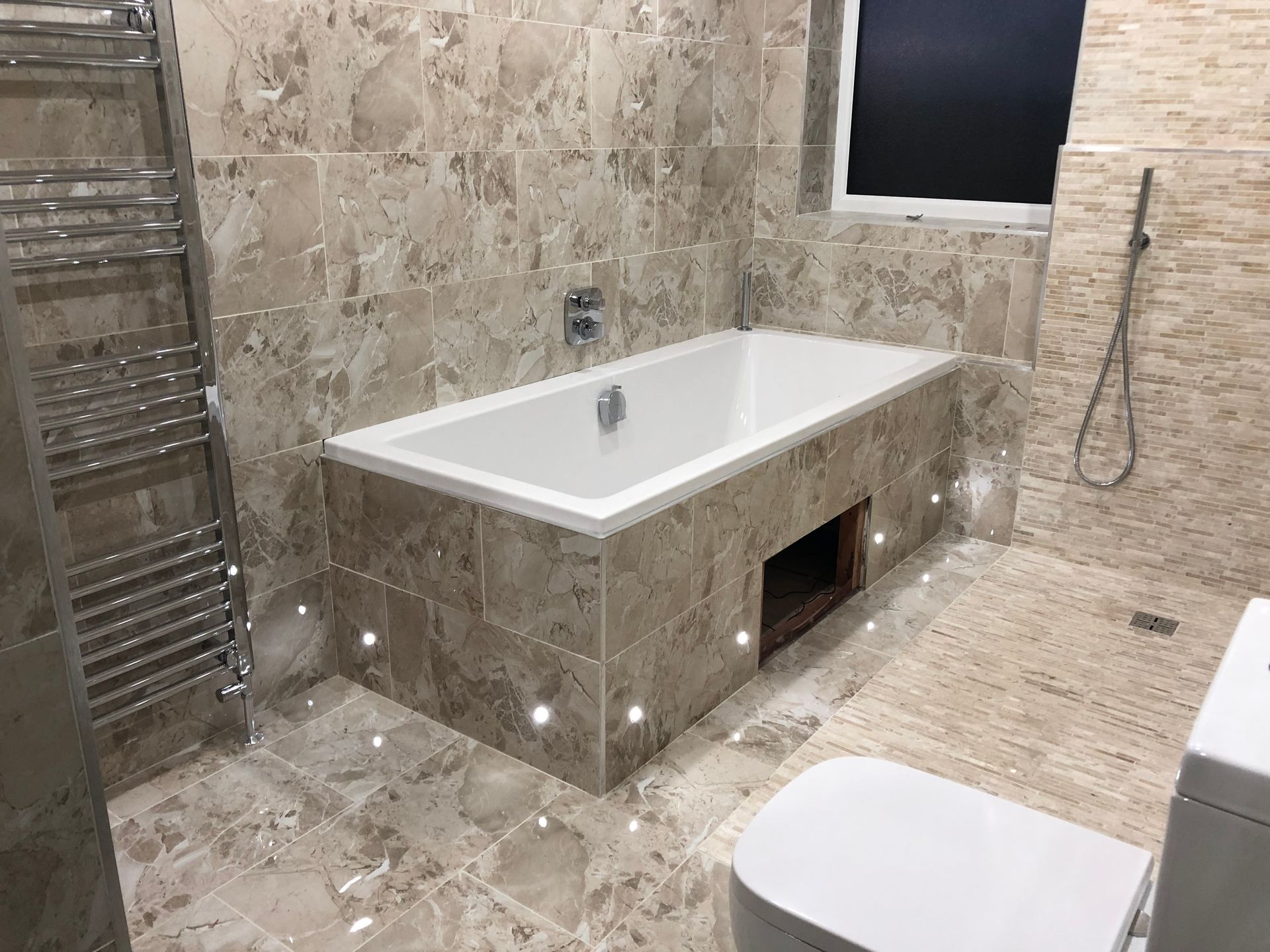 Modern bathroom with tiled walls, a bathtub, and a toilet.