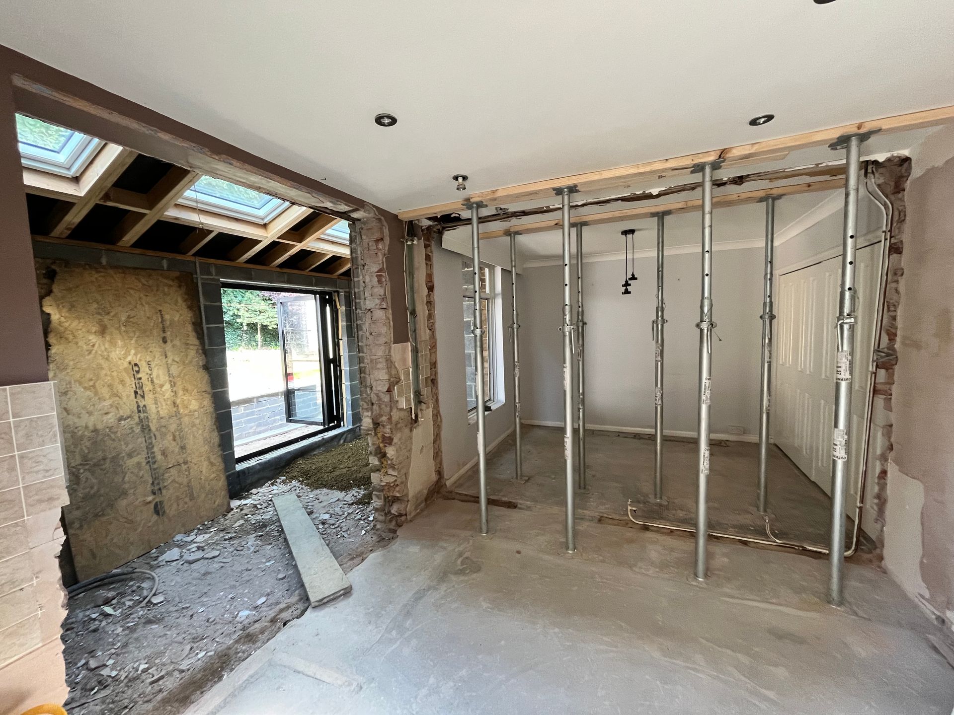 Interior room undergoing renovation, showing support beams and exposed walls.