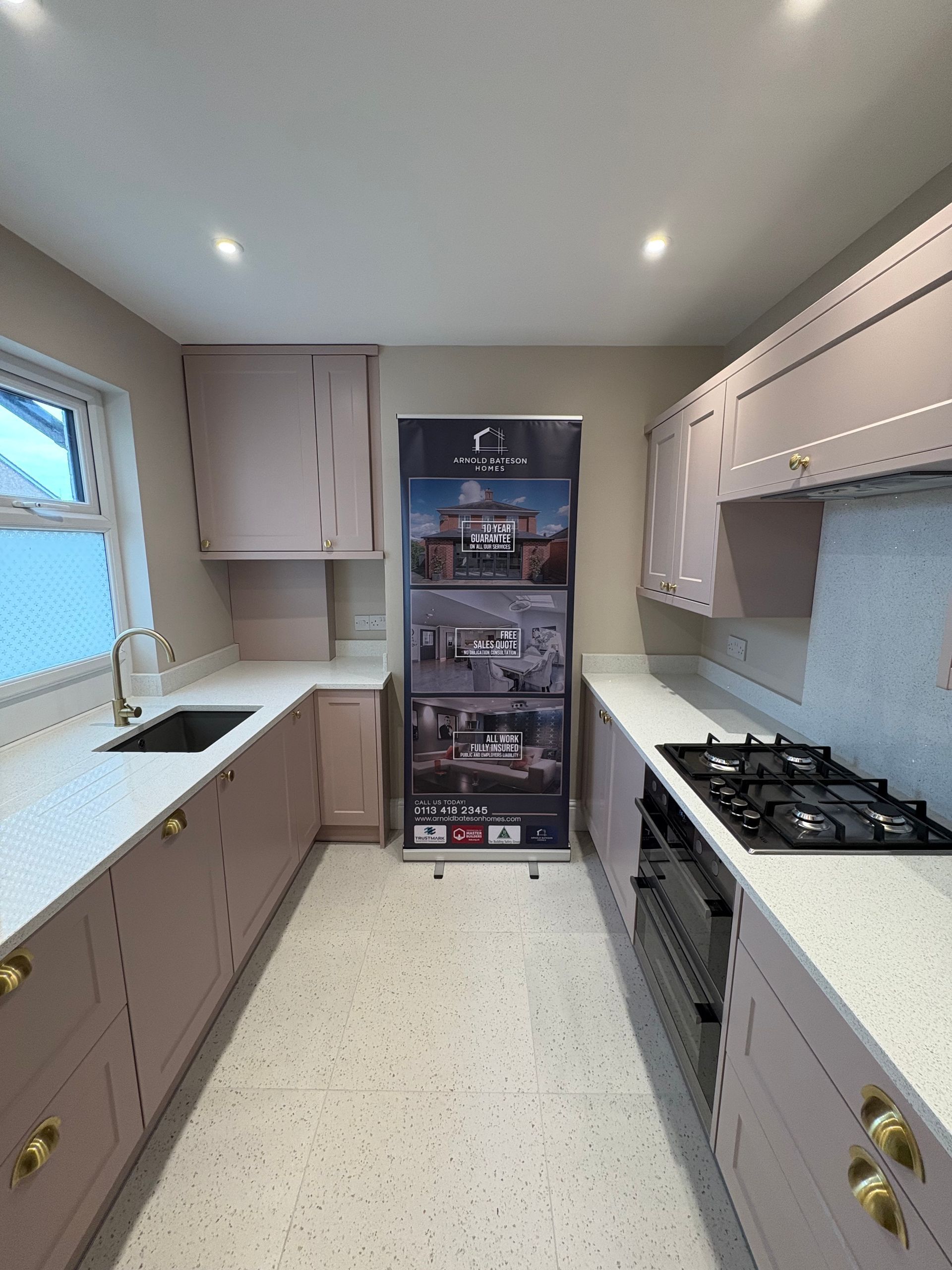 Pink kitchen cabinets with white countertops and a black stove.