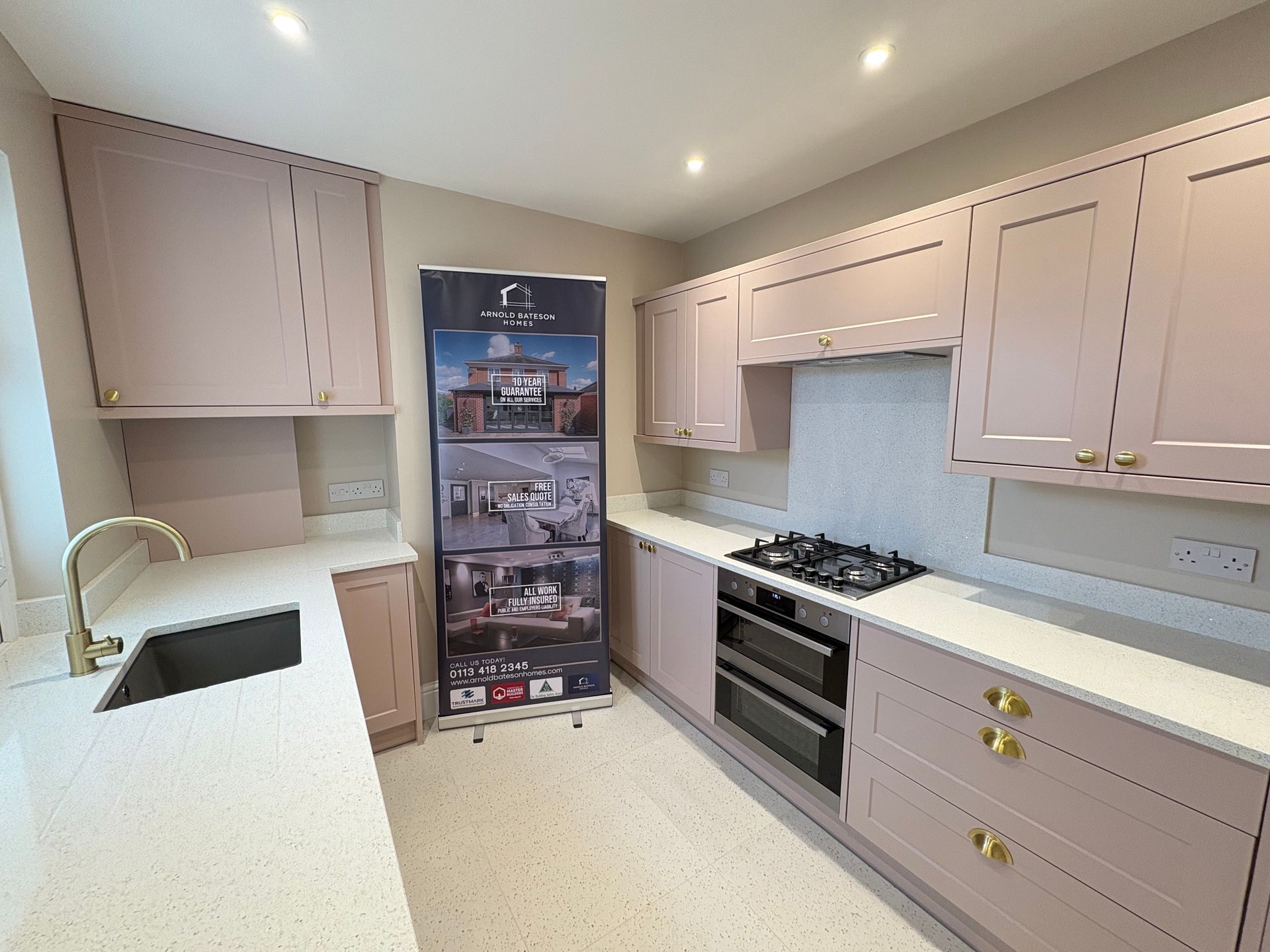 Pink kitchen cabinets with white countertops and a stainless steel sink.