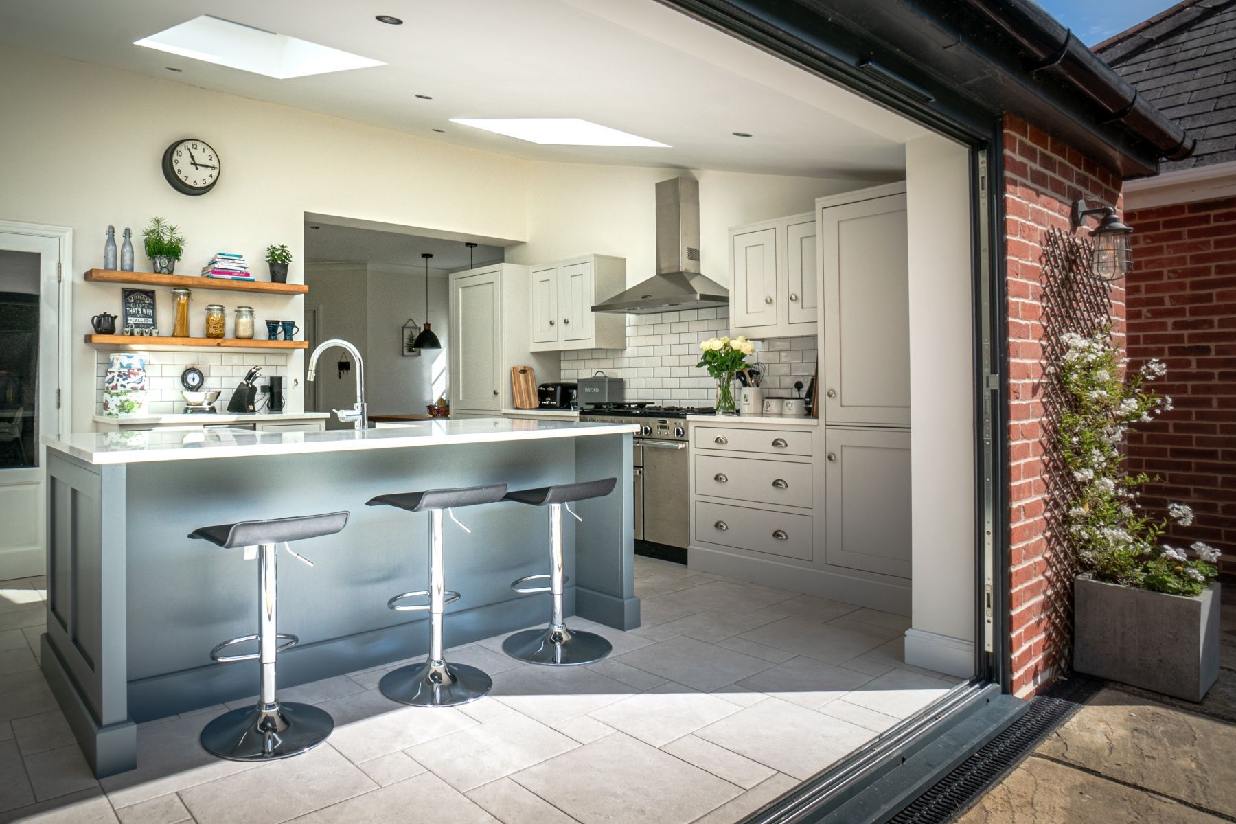 Modern kitchen with a gray island, white cabinets, and open sliding doors to the outdoors.
