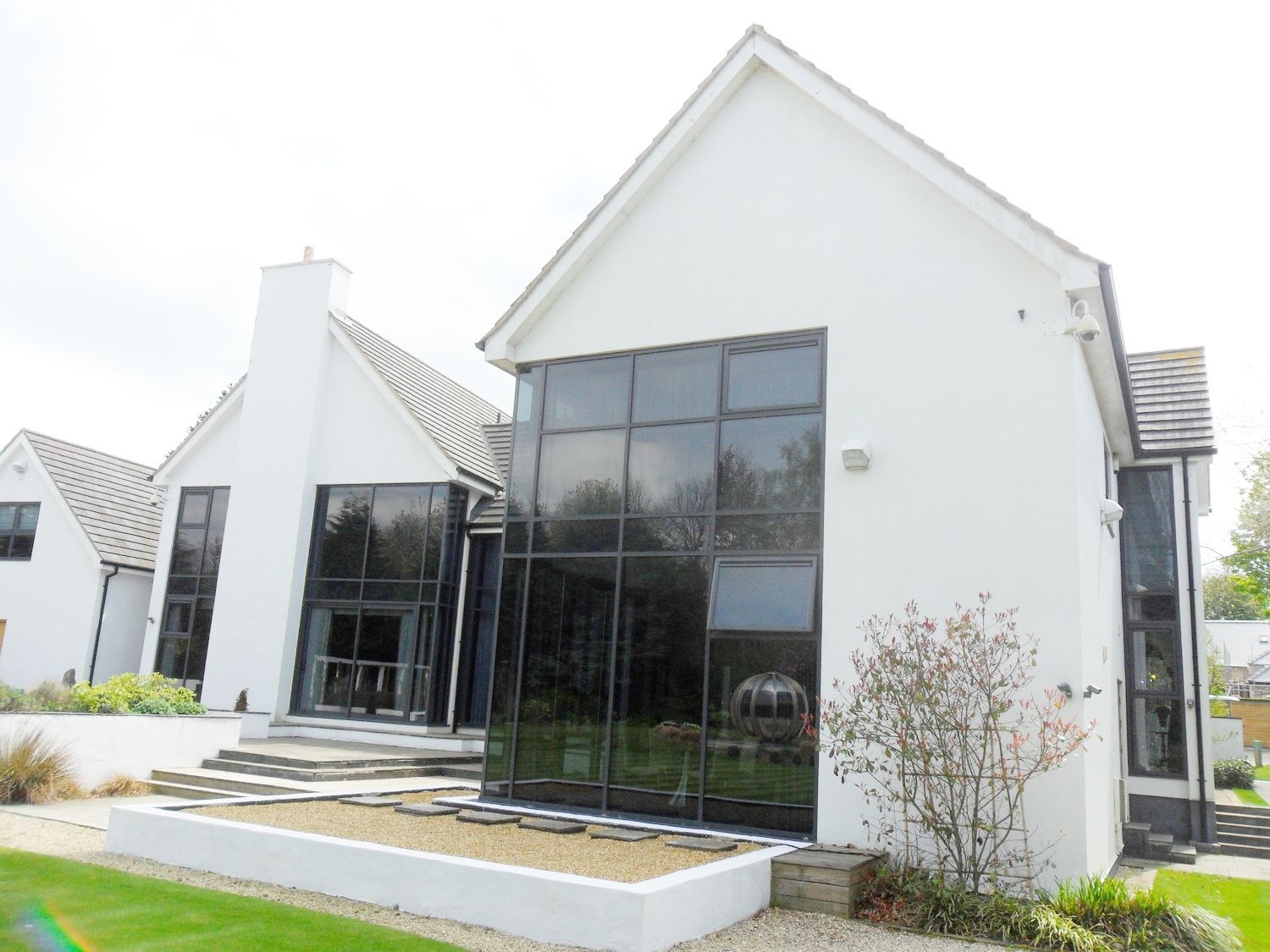 White house with large black glass windows. Green lawn and steps lead up to the entrance.