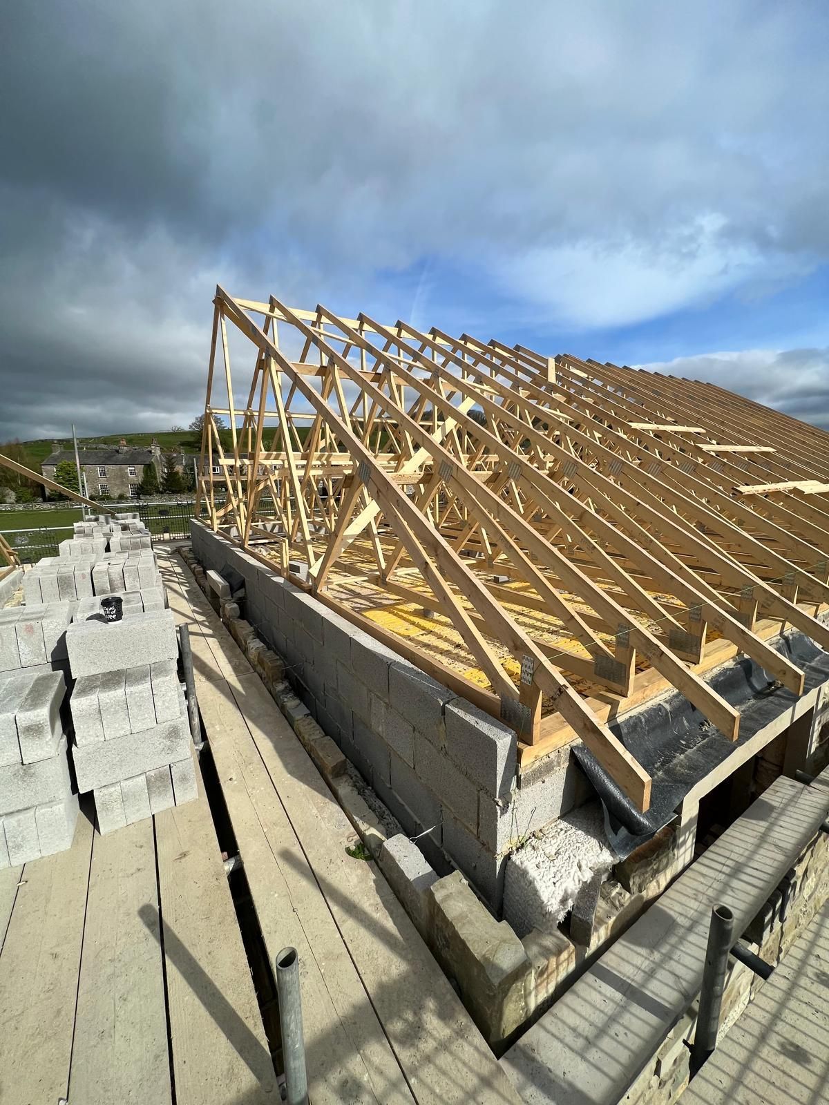 Roof trusses being installed on a building under construction on a cloudy day.