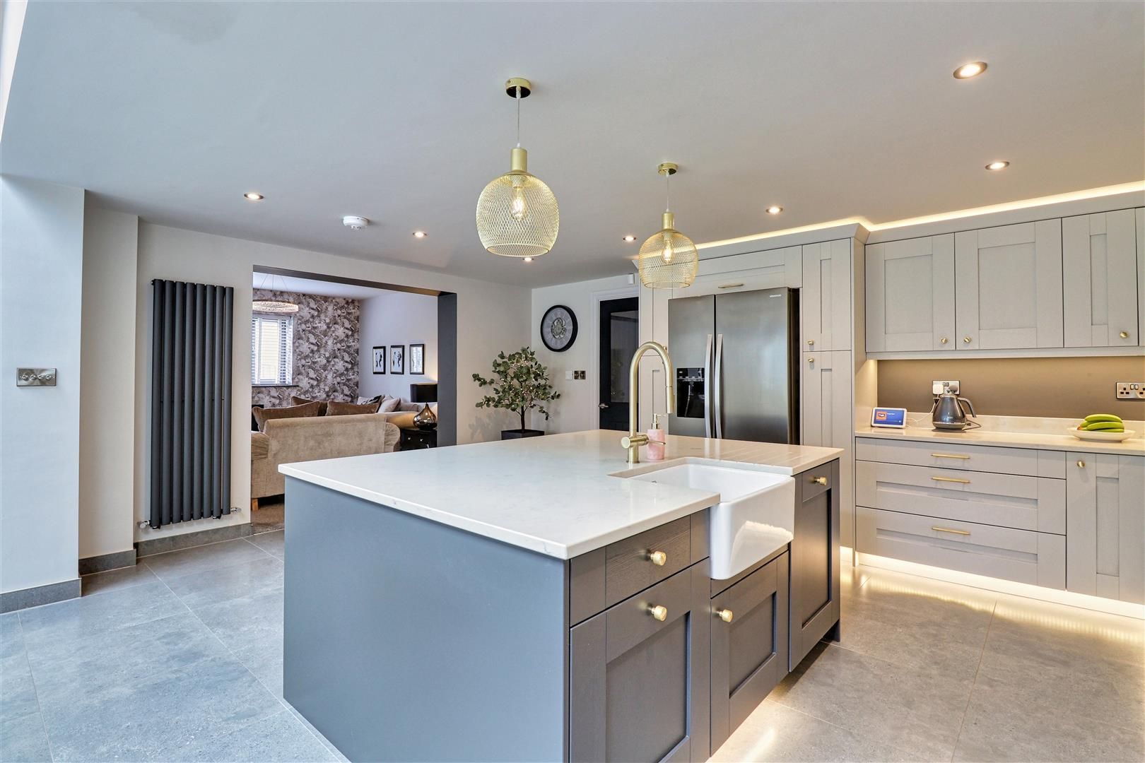 Modern kitchen with gray island, white countertops, and pendant lights.