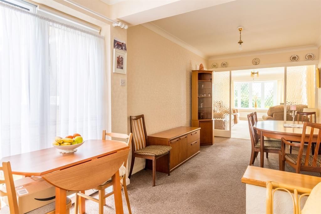 Dining area with two wooden tables, a cabinet, and a doorway to a living room.