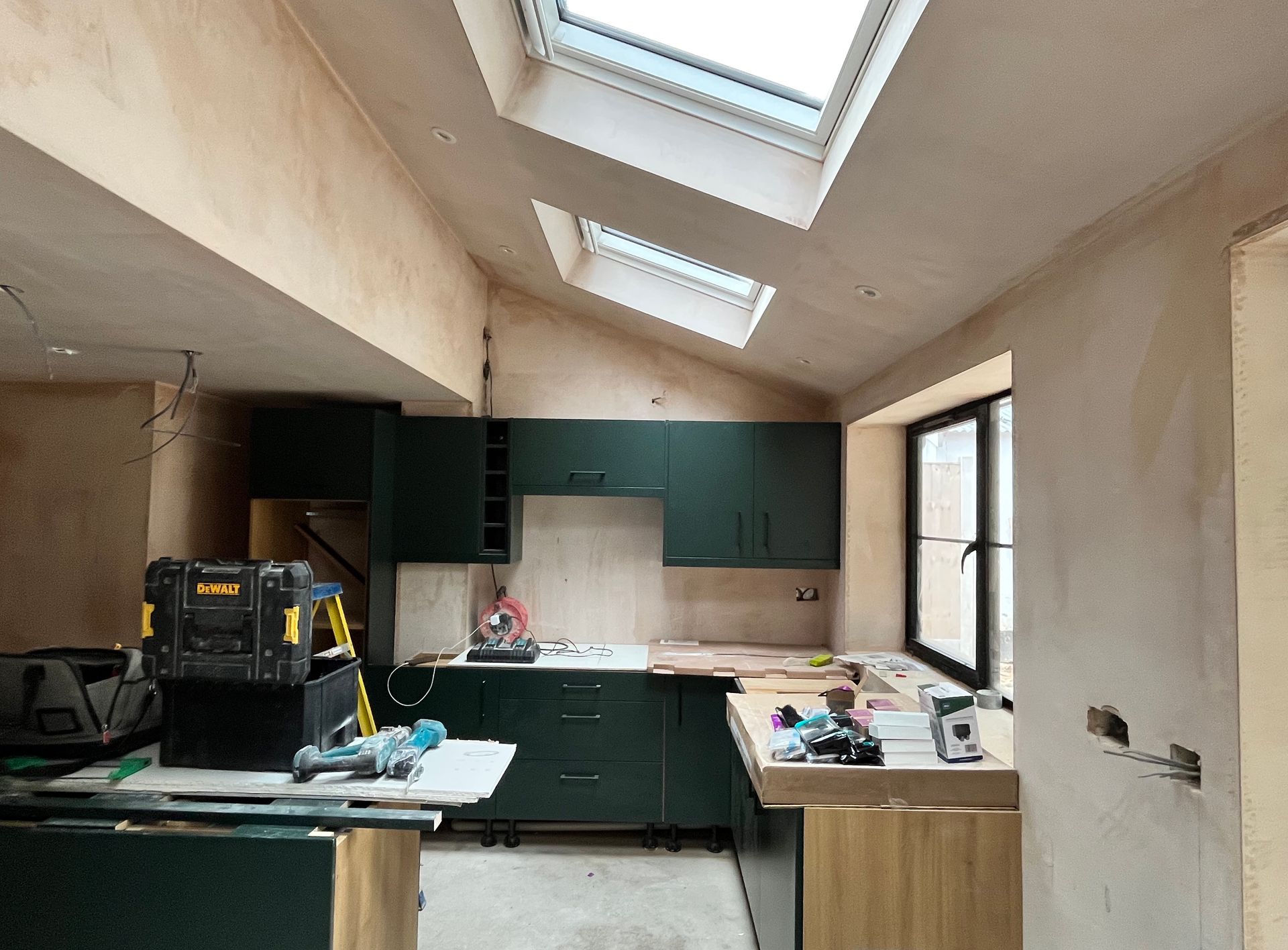 Kitchen under construction with green cabinets, skylights, and tools.