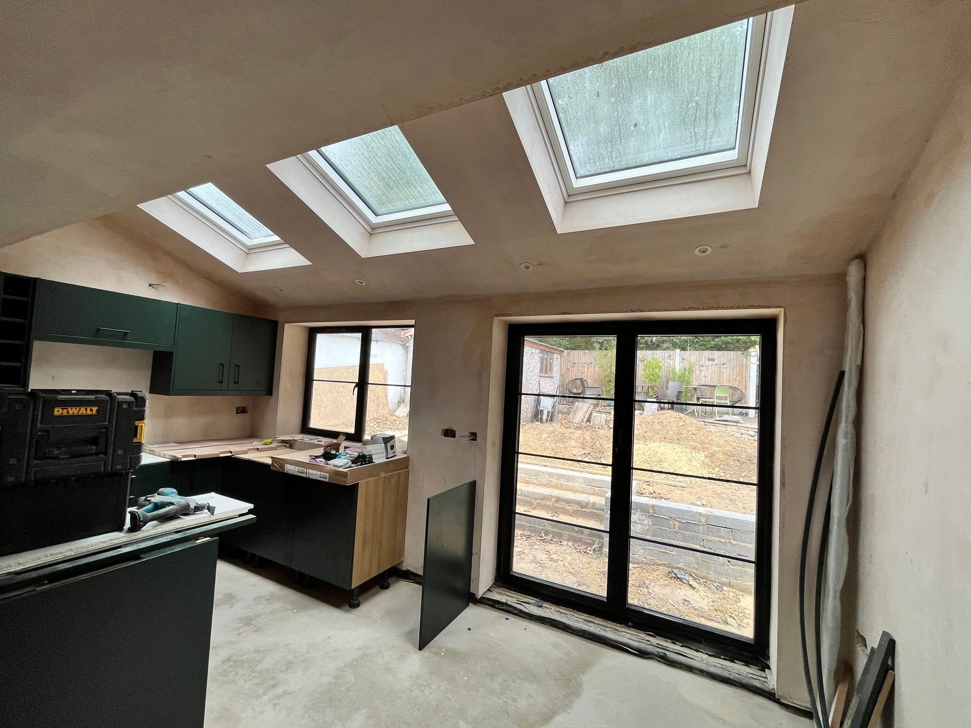 Kitchen under construction with dark cabinets, skylights, and sliding glass doors.