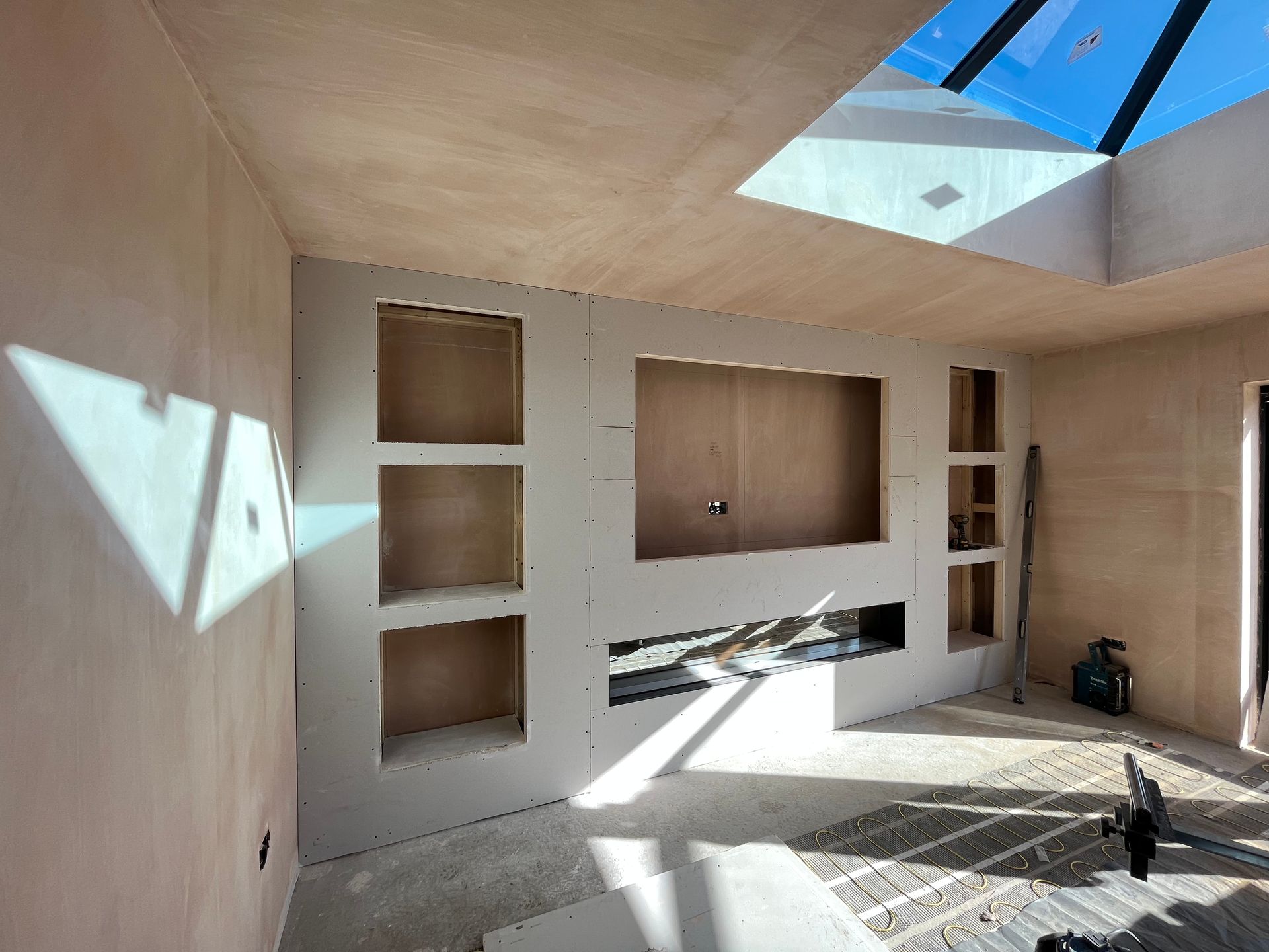 Interior construction with recessed shelves and a large central space; light from skylight.