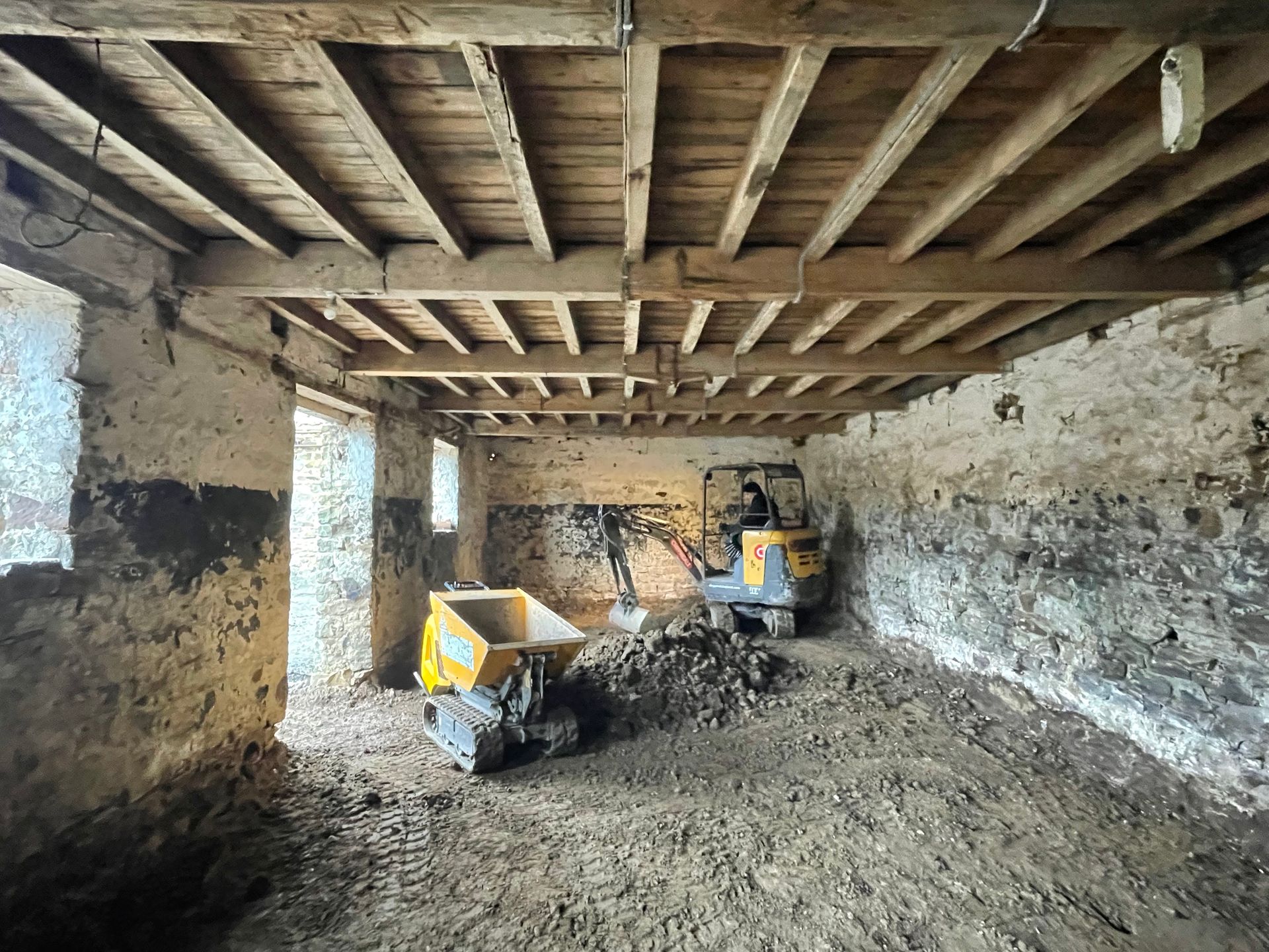 Interior of old building under construction, with construction equipment, exposed wooden beams.