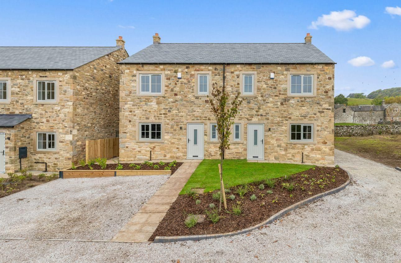 Stone-faced townhouses with gray roofs and windows, centered path to light gray front doors, small front lawns