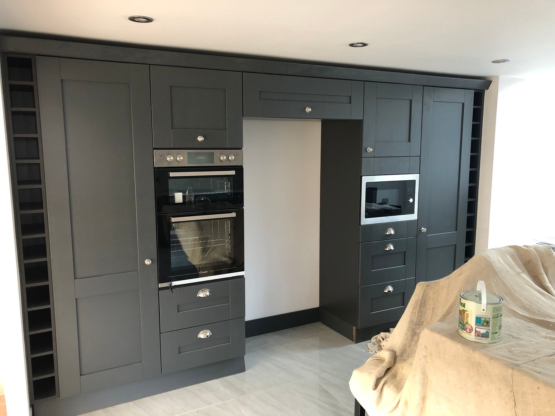 Dark grey kitchen cabinetry with integrated oven, microwave, and wine racks.