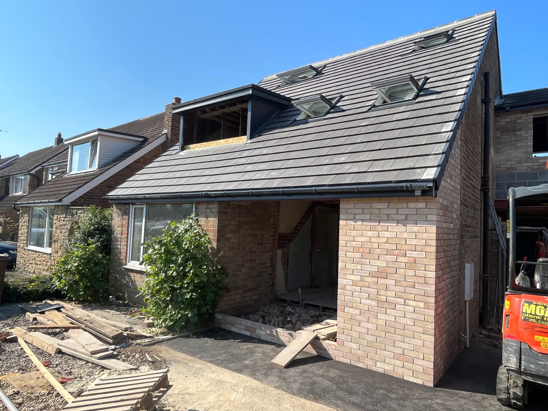 New construction house with brick exterior, gray roof, and a clear blue sky.