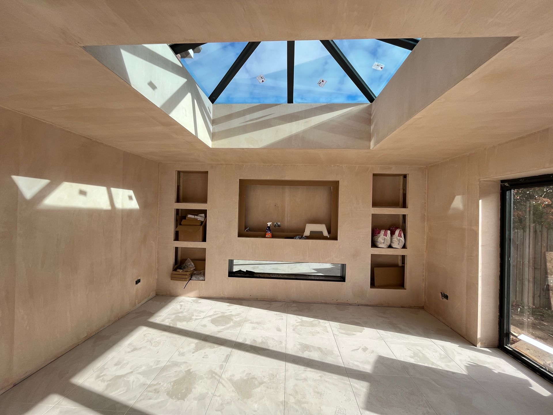 Interior room with a skylight, recessed shelves, and unfinished walls.