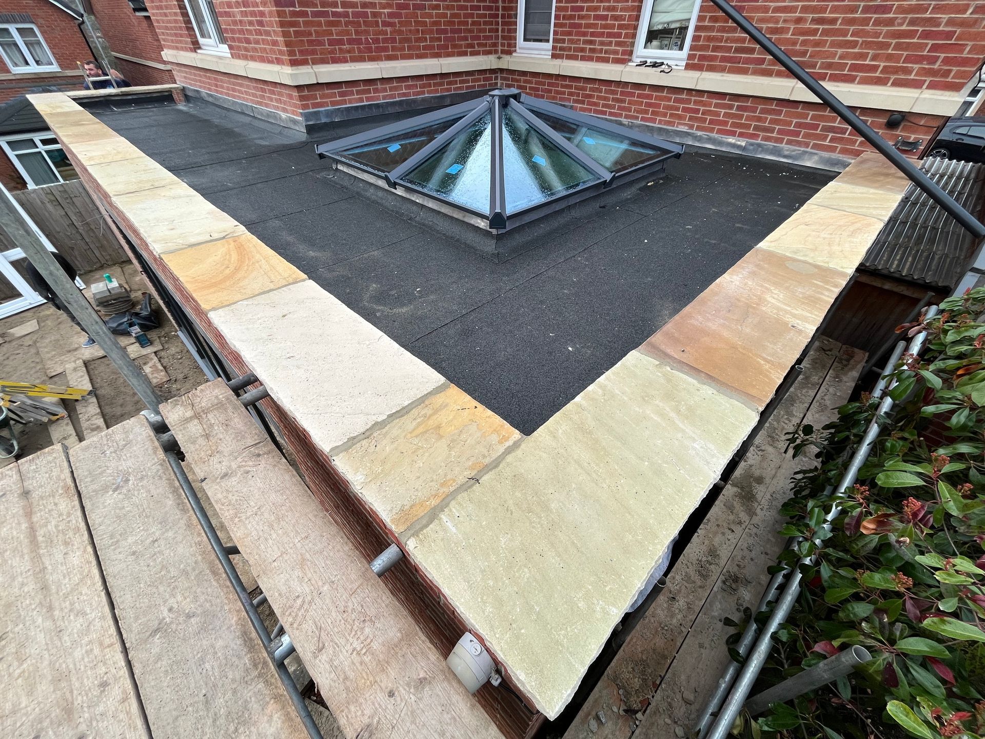 Flat roof with sandstone coping, a skylight, and scaffolding.