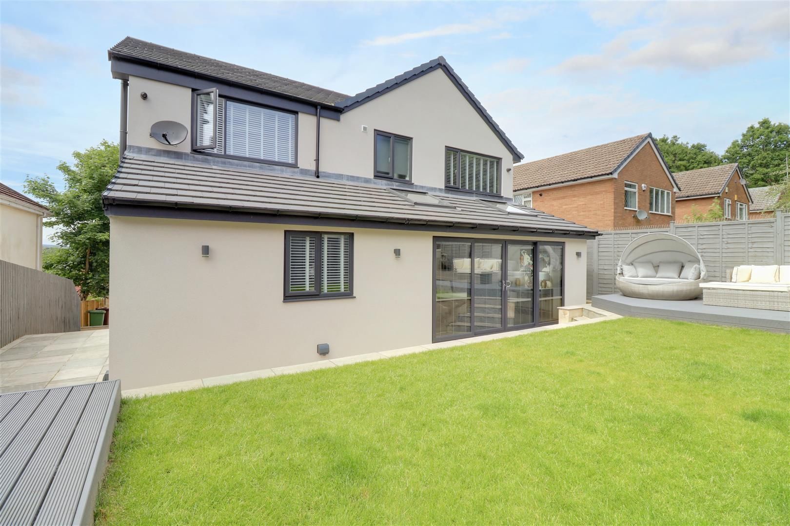 Back of a modern house with gray stucco, black trim, and a green lawn.