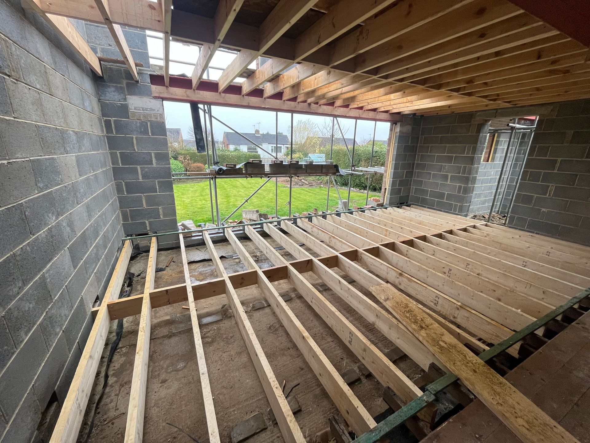 Construction site: Wooden floor joists being installed inside a block-walled structure.