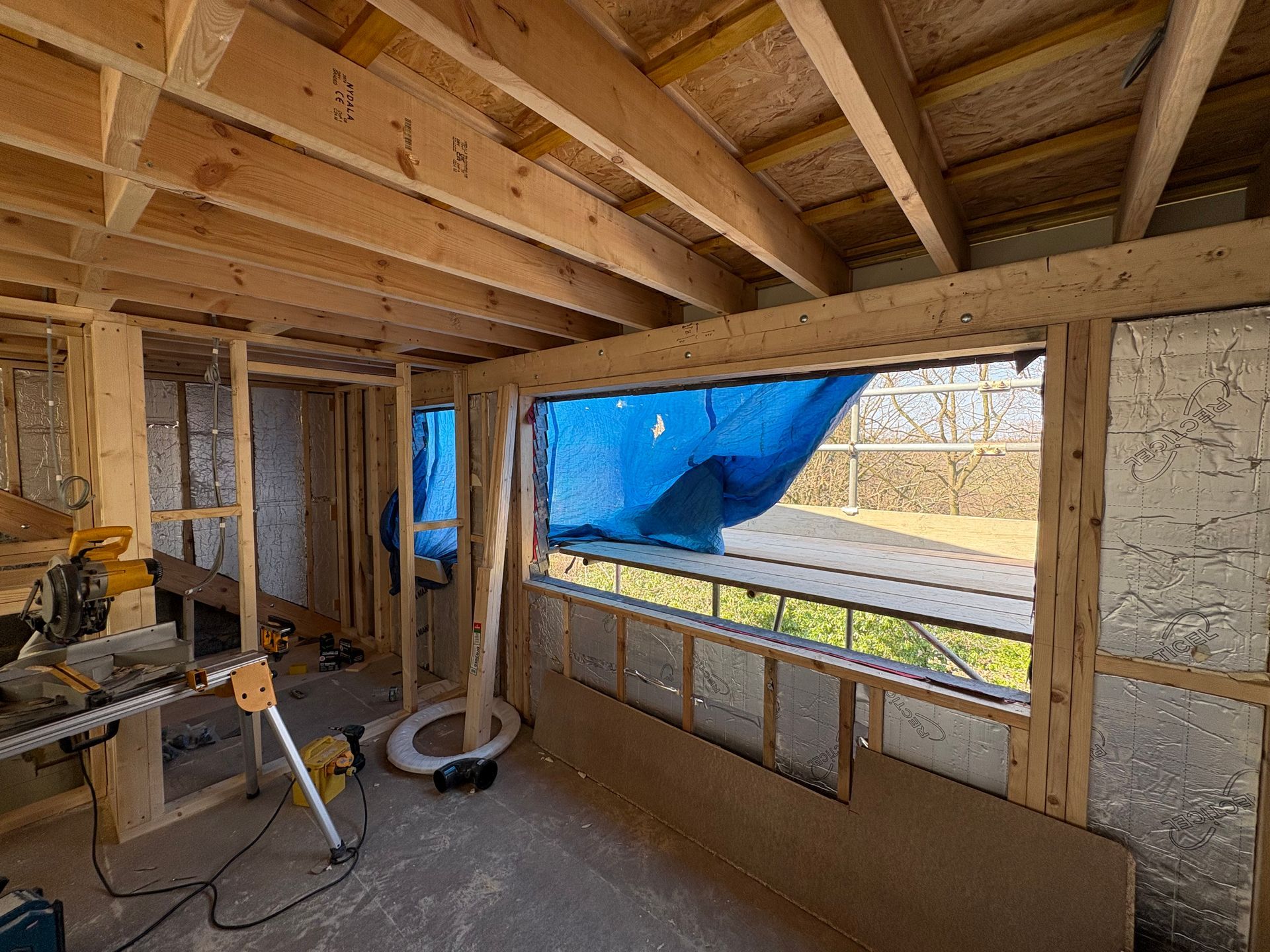 Interior framing of a building under construction, with a window looking outside.
