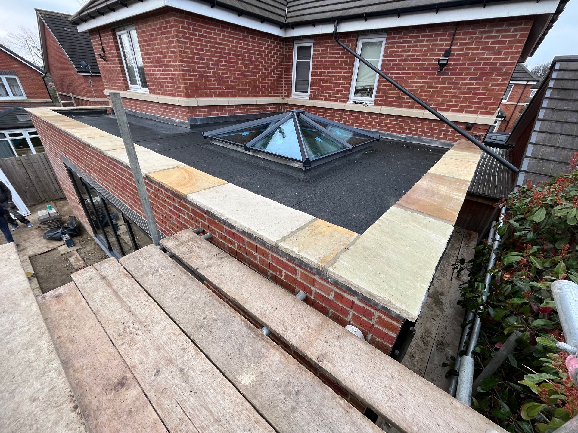 Brick extension with skylight and flat roof, scaffolding in view.