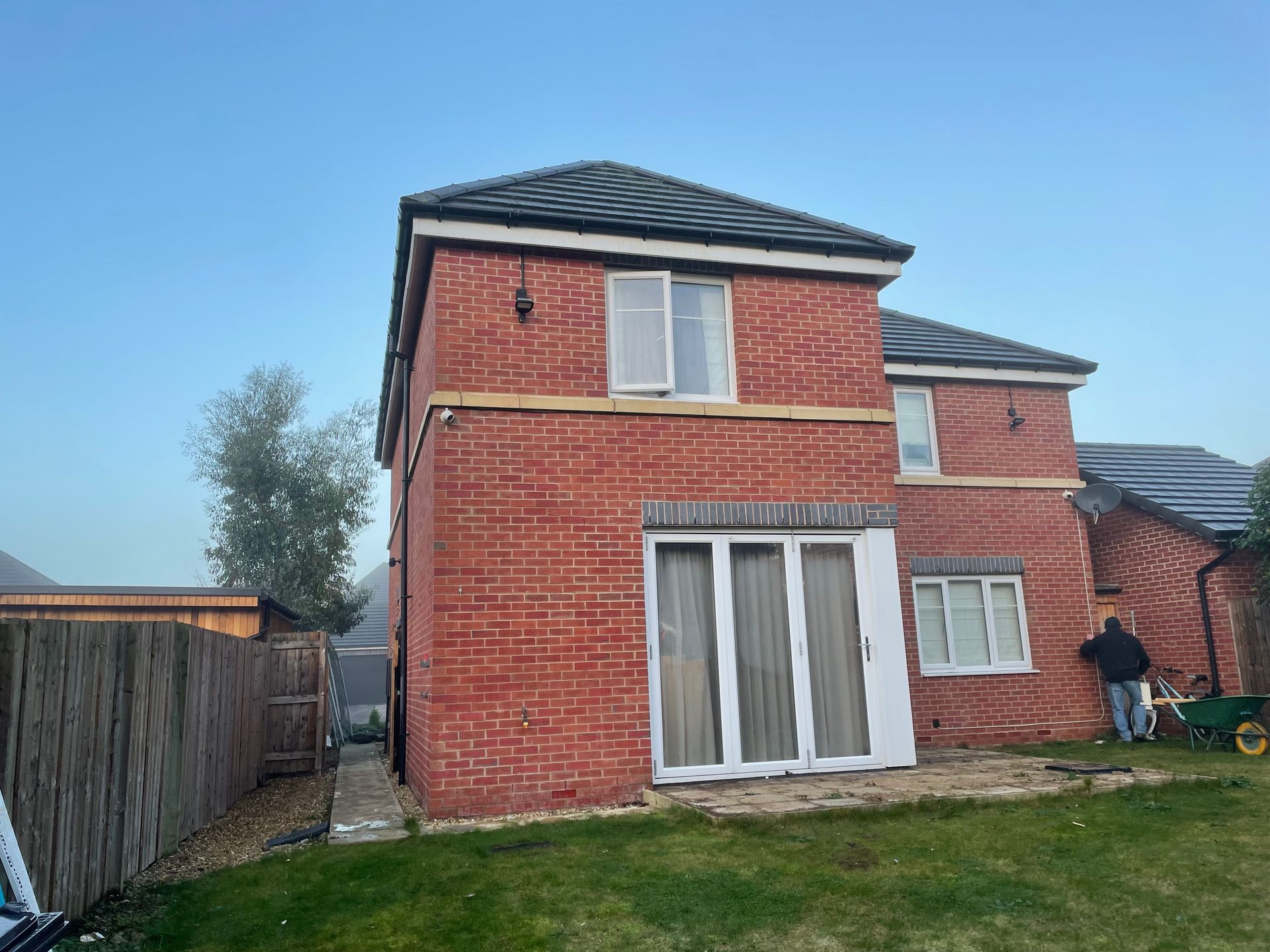 Red brick house with white trim, two stories, and a person working outside.