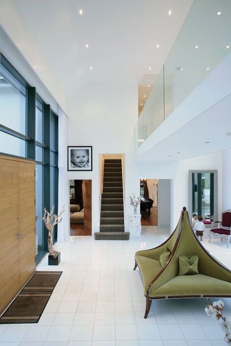 Modern home foyer with a green sofa, large portrait, and a staircase.