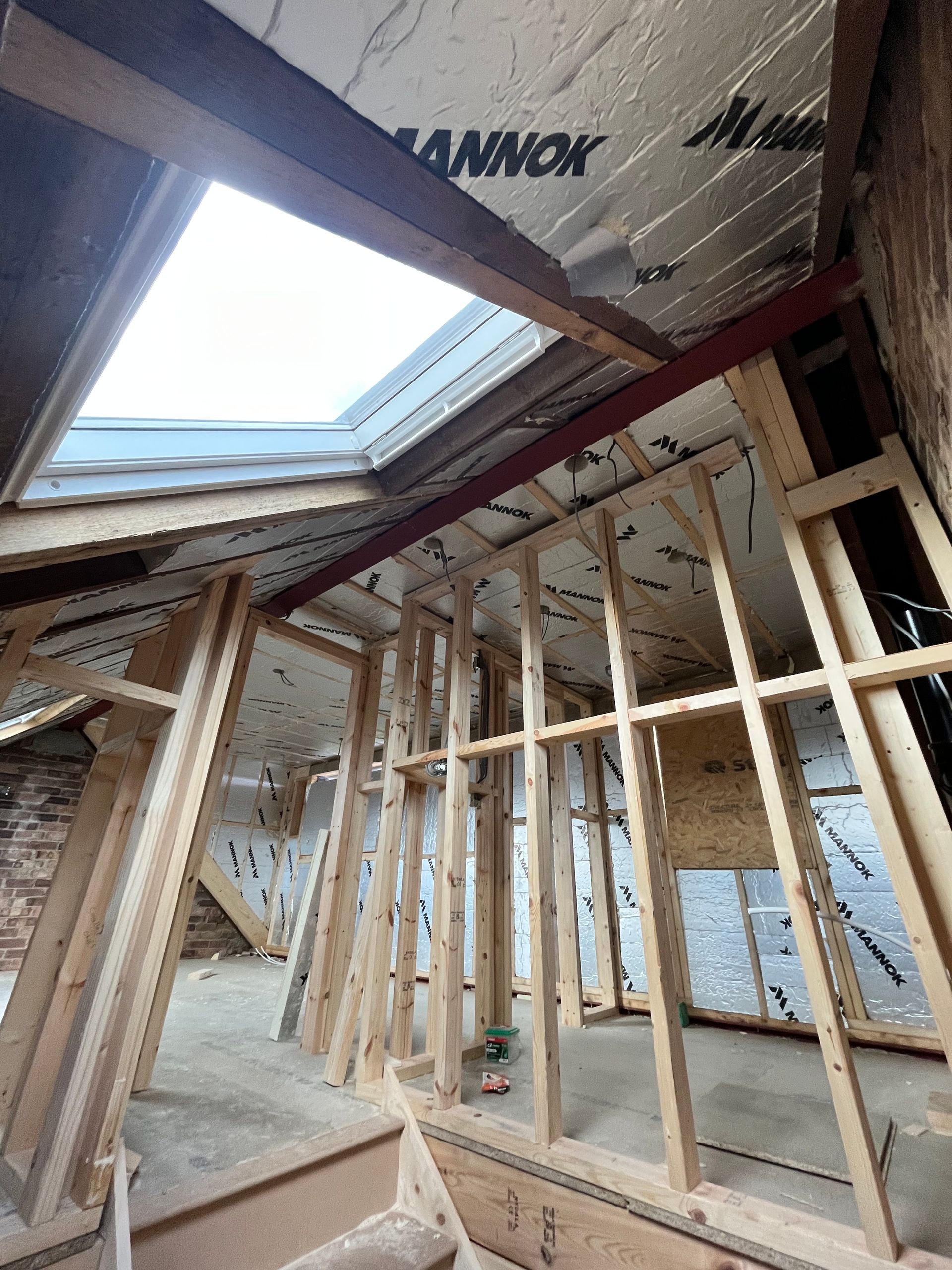 Interior view of a room under construction with wooden framing, a skylight, and insulation.