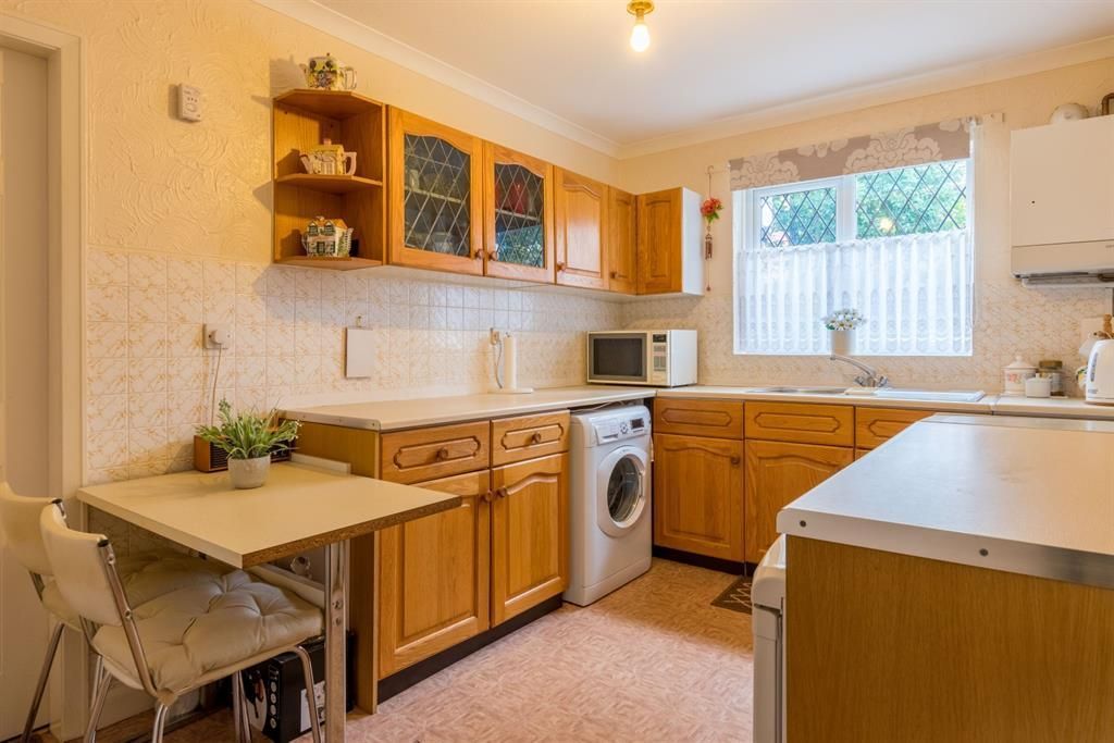 Kitchen with wooden cabinets, appliances, and a small table.