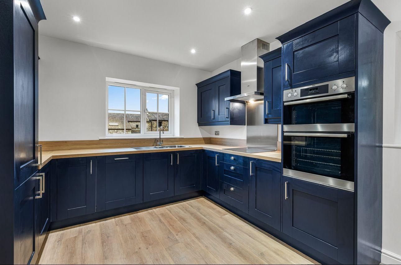 Blue kitchen with wooden countertops, stainless steel appliances, and a window.