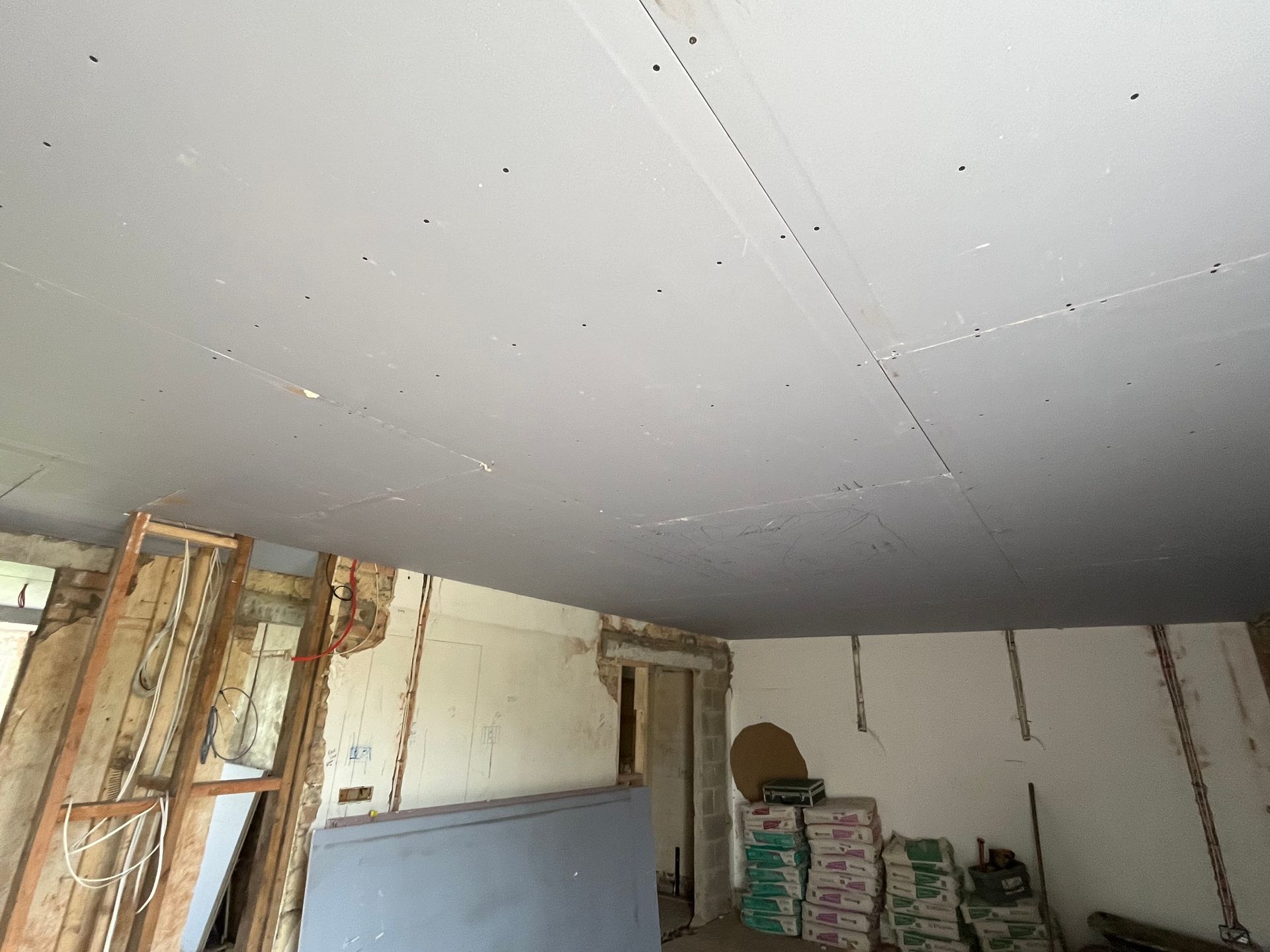 Interior construction: Drywall ceiling installed, room with unfinished walls, exposed framing and materials.