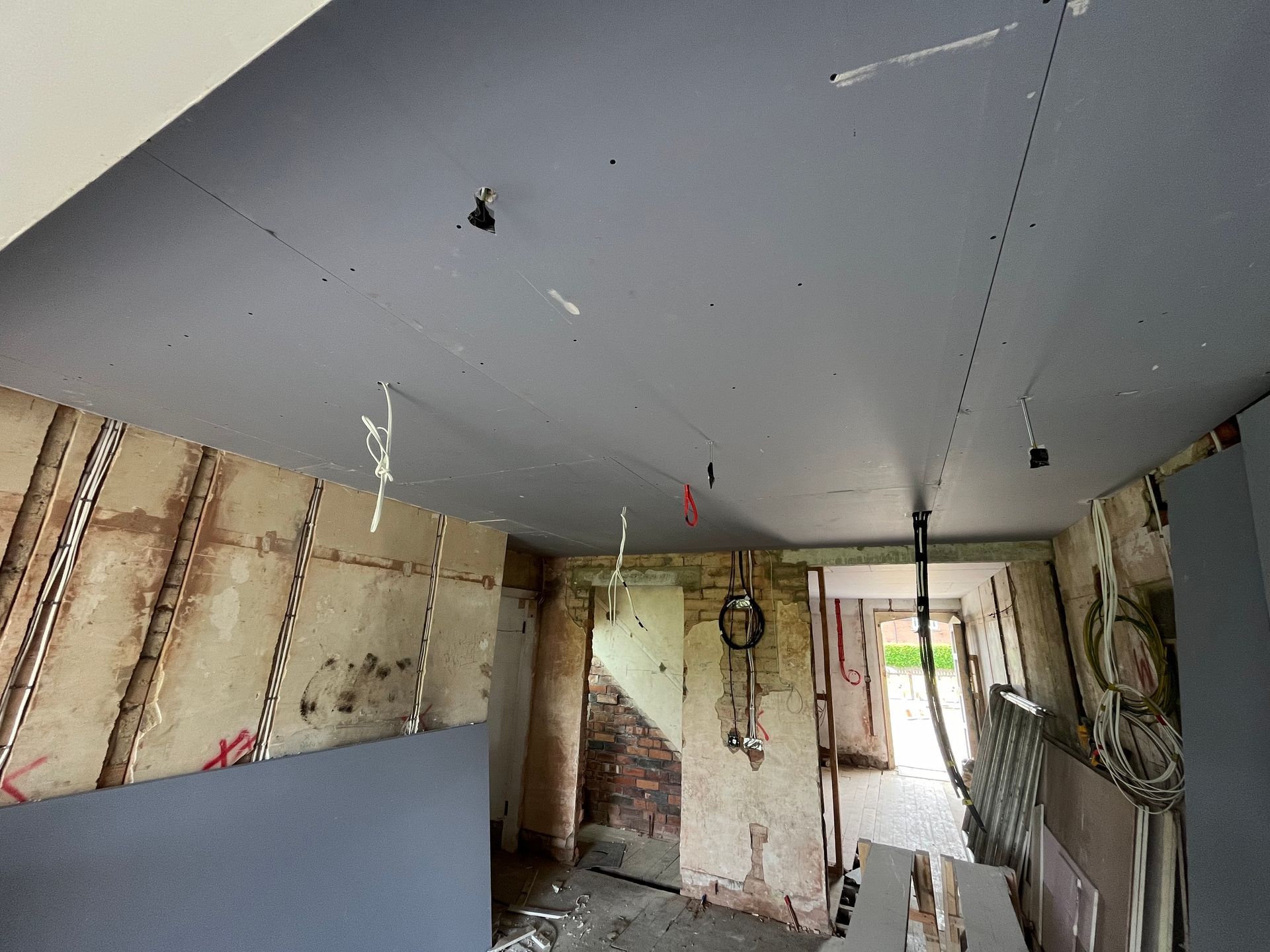 Interior view of a room under renovation. Gray ceiling, exposed walls, and doorway to a stairway.