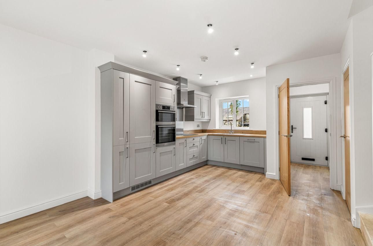 Gray kitchen with light wood floors, doorway, and white walls.