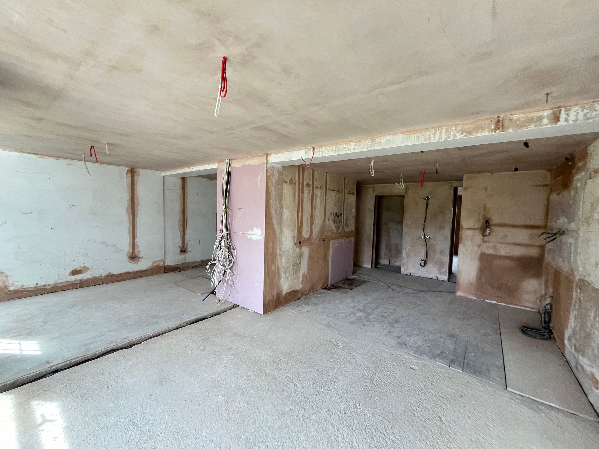 Interior room under construction, with exposed walls, wiring, and unfinished surfaces.