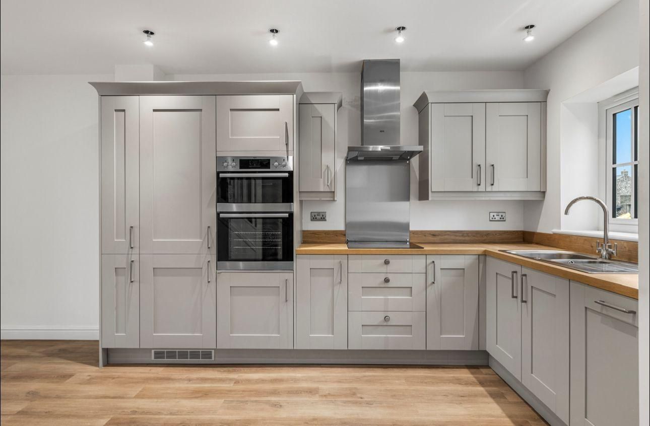 Modern kitchen with gray cabinets, stainless steel appliances, and wood countertops and floors.