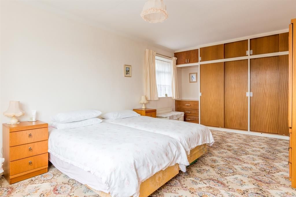 Bedroom with twin beds, wooden furniture, and patterned carpet.