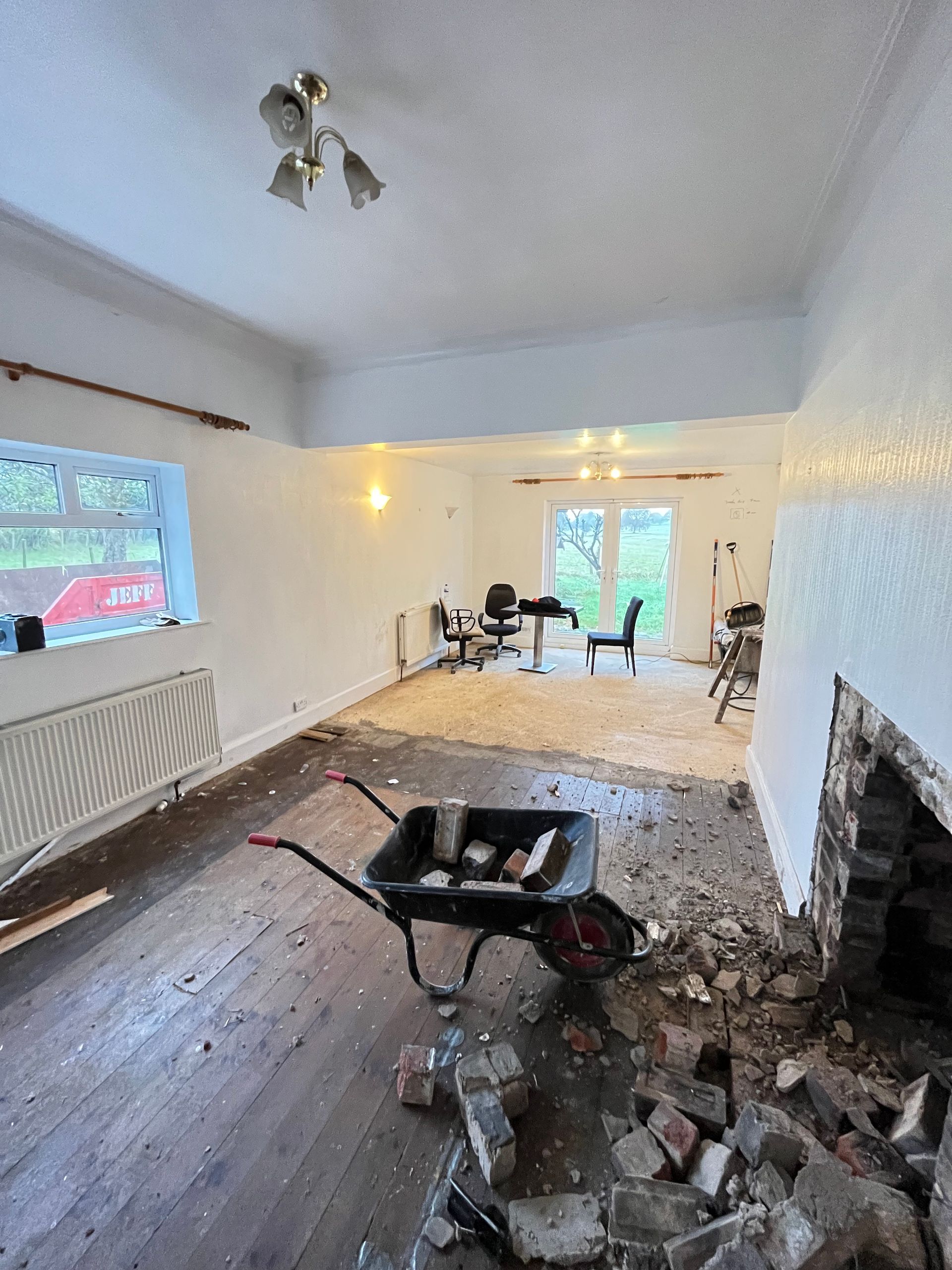 Room under renovation with exposed brick, wheelbarrow, and debris.