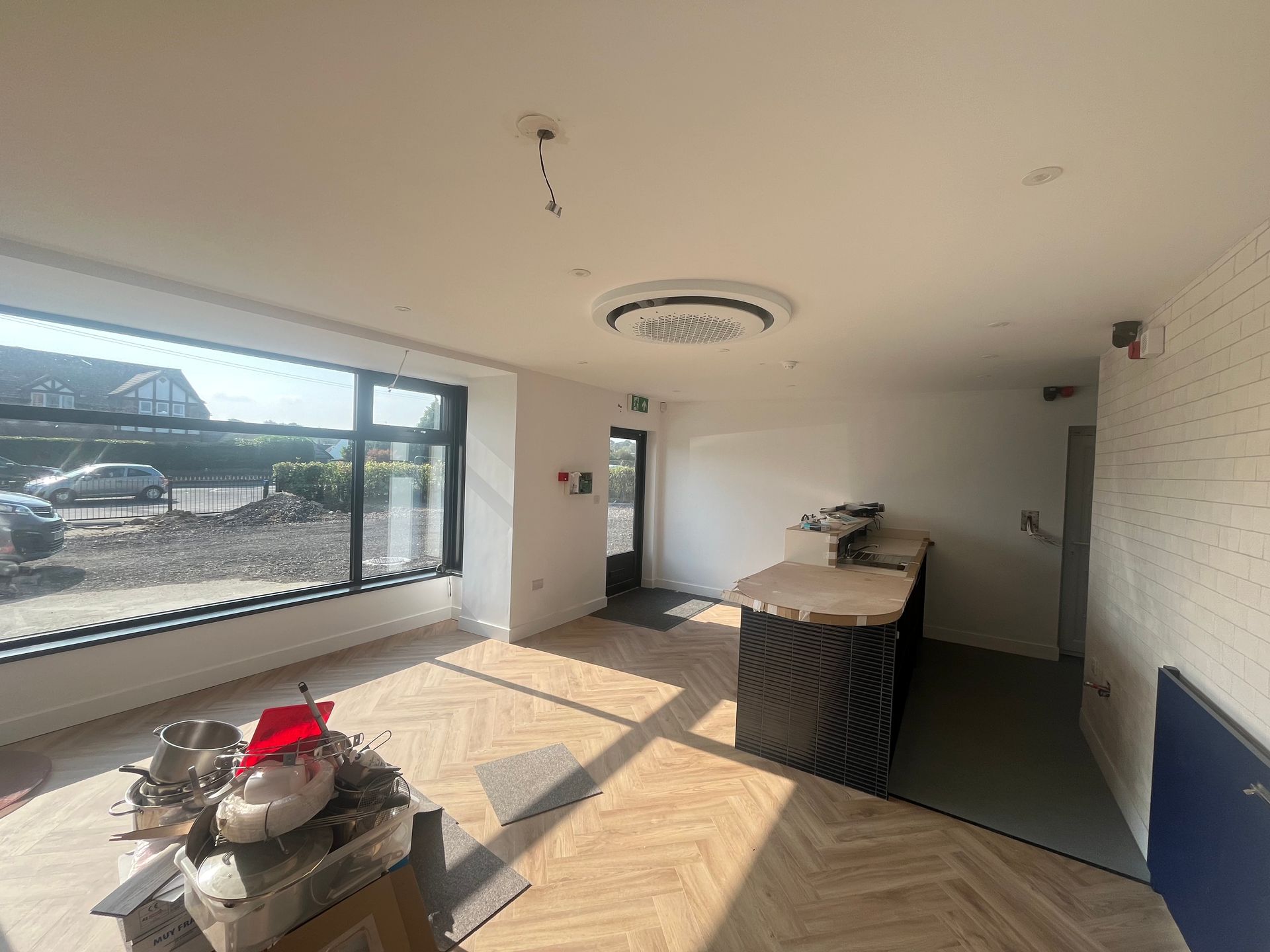 Empty commercial space with large windows, counter, and light wood floor.