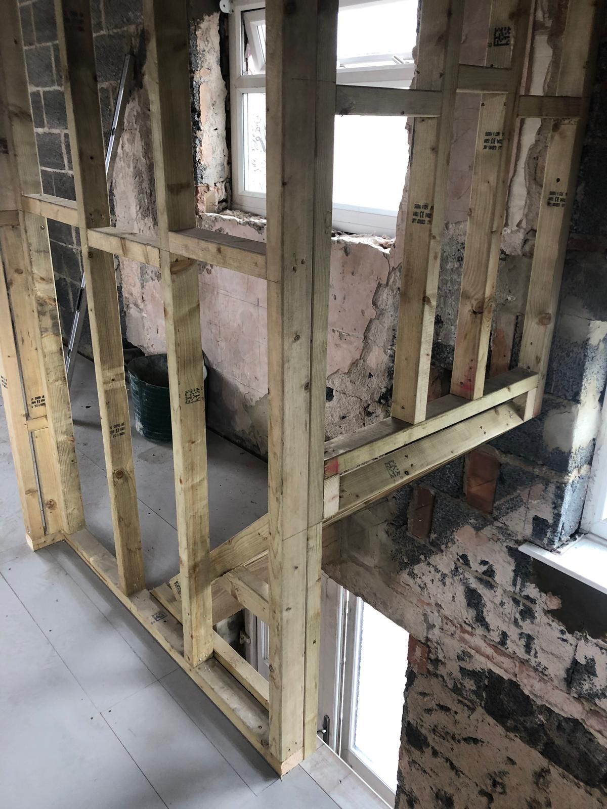 Wooden framing for a wall and doorway being constructed around a window.