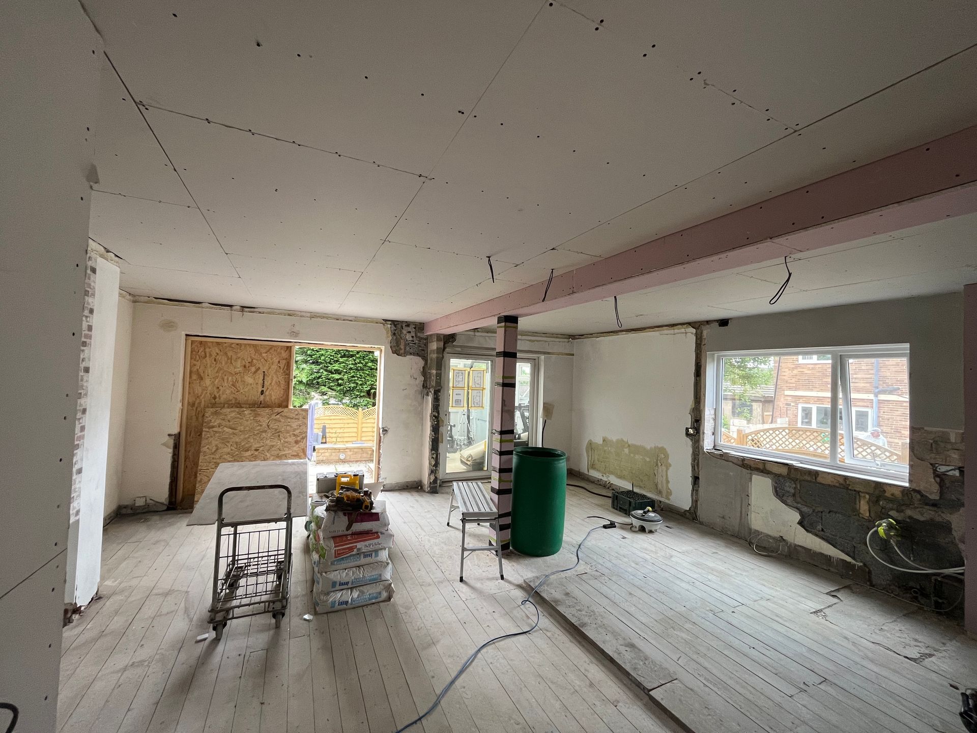 Interior undergoing renovation with exposed walls, flooring, and ceiling beams.