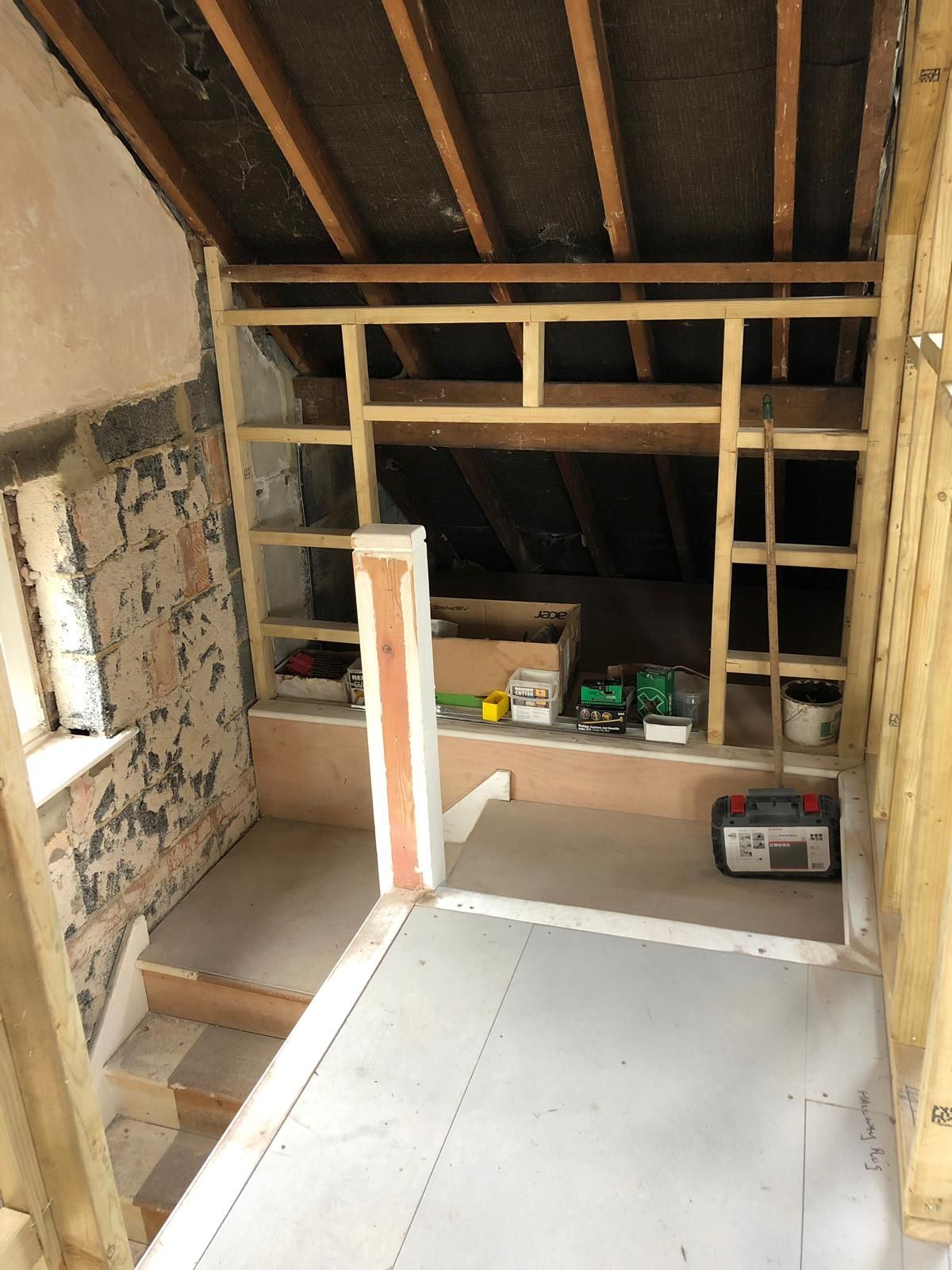 Interior construction: Wooden frame with shelves, small platform, and tools. Attic space in renovation.
