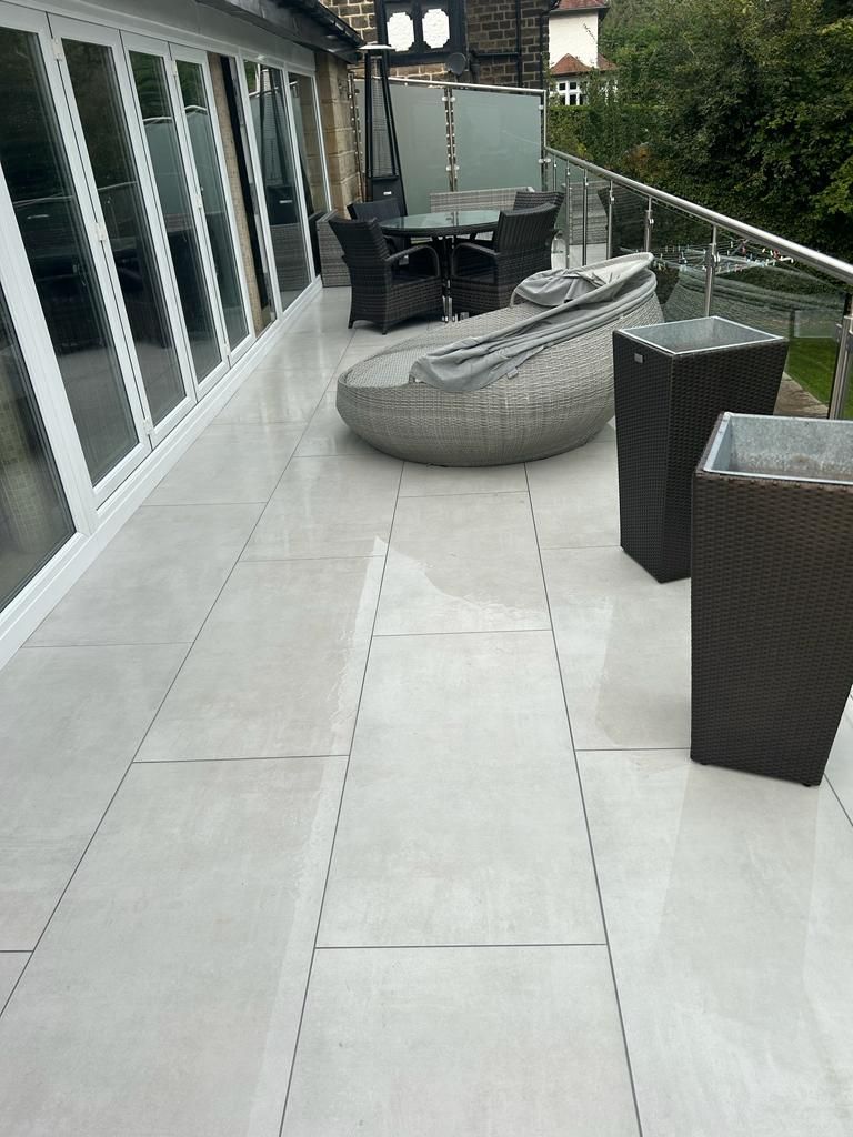 Patio with light gray tiled floor, modern furniture, and glass railings.